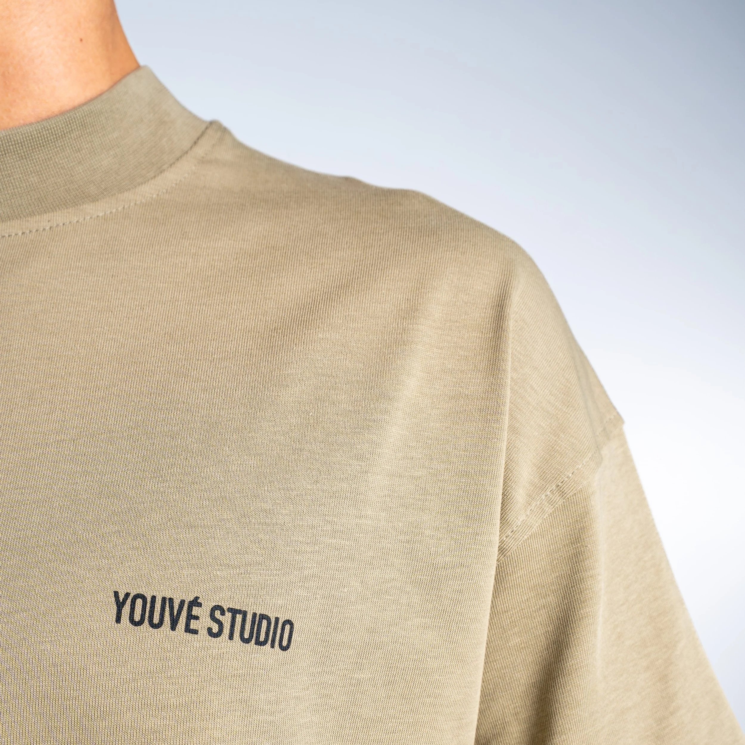Close up of a heavyweight 100% cotton t-shirt, with oversized fit and chunky collar and a black Youvé Studio logo print on the left chest.