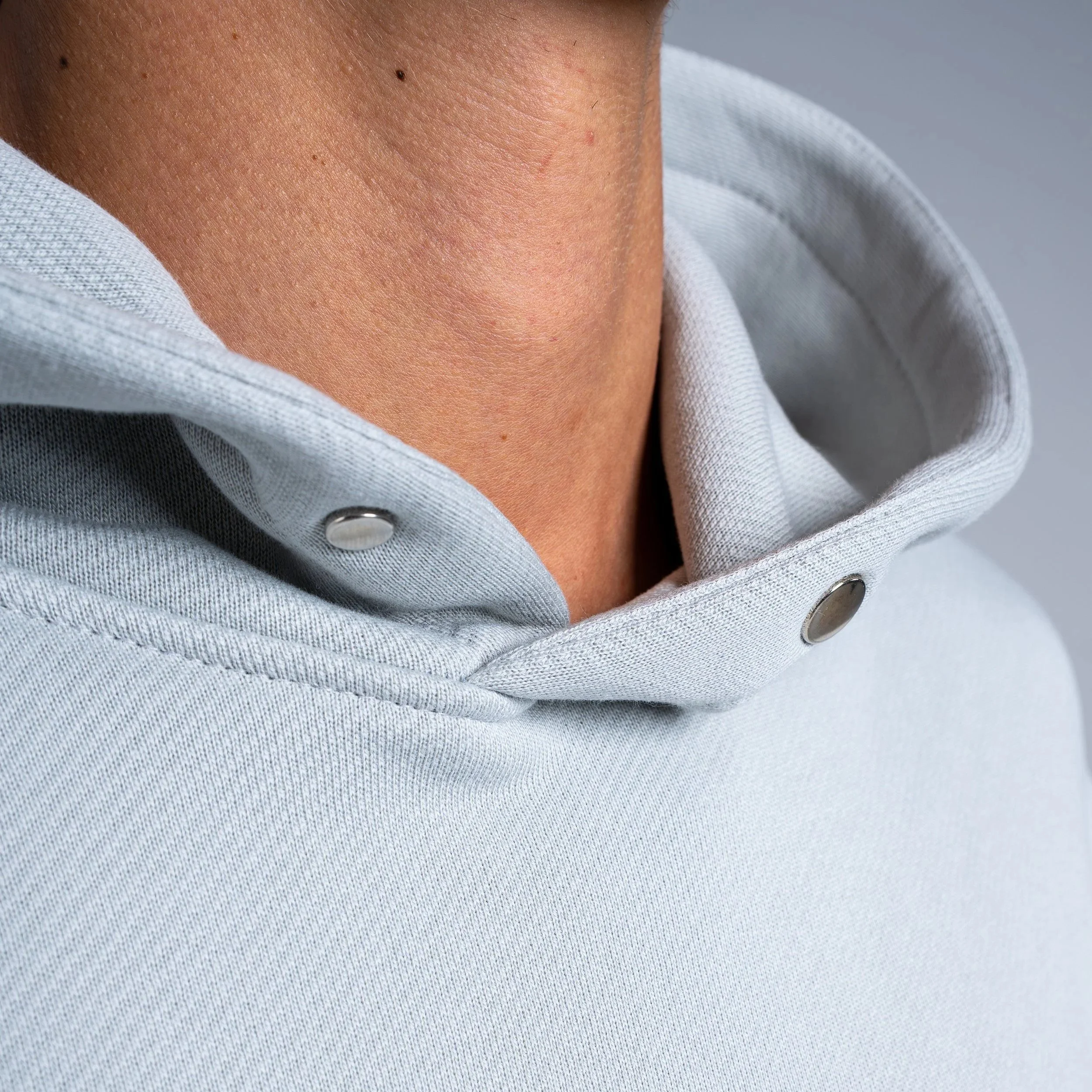 Close-up of a person wearing a light gray hoodie, with the focus on the neck and collar area.