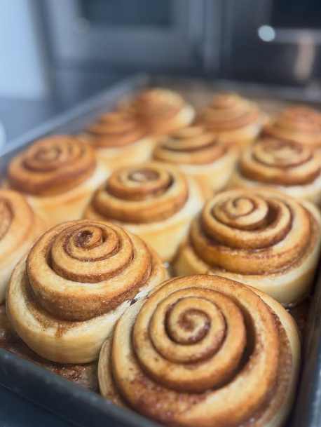 Fresh baked cinnamon rolls with swirled dough in a tray