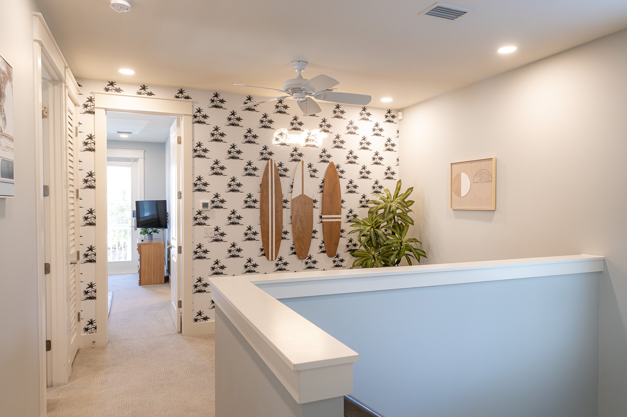 Another view of the Second Set game room featuring a foosball table, surfboards, tropical palm wallpaper, and coastal decor.