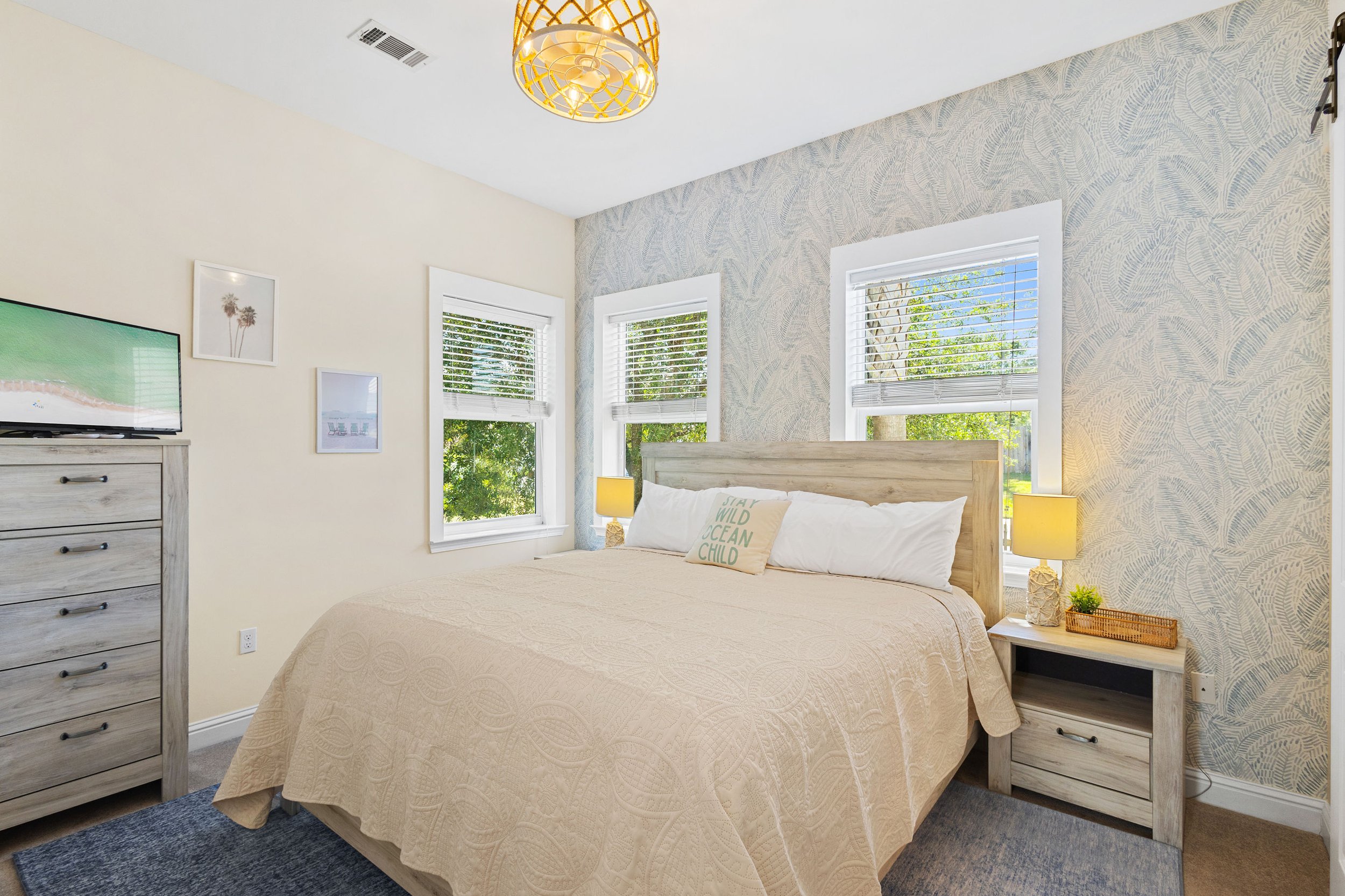 Relaxing king bedroom at Salty Surf on 30A featuring coastal style, comfortable bedding, natural light, and an en-suite bathroom. 