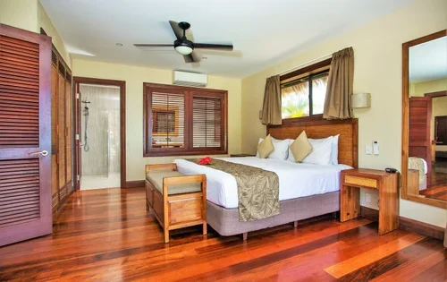 Hotel room with a large bed, wooden furniture, and a ceiling fan.