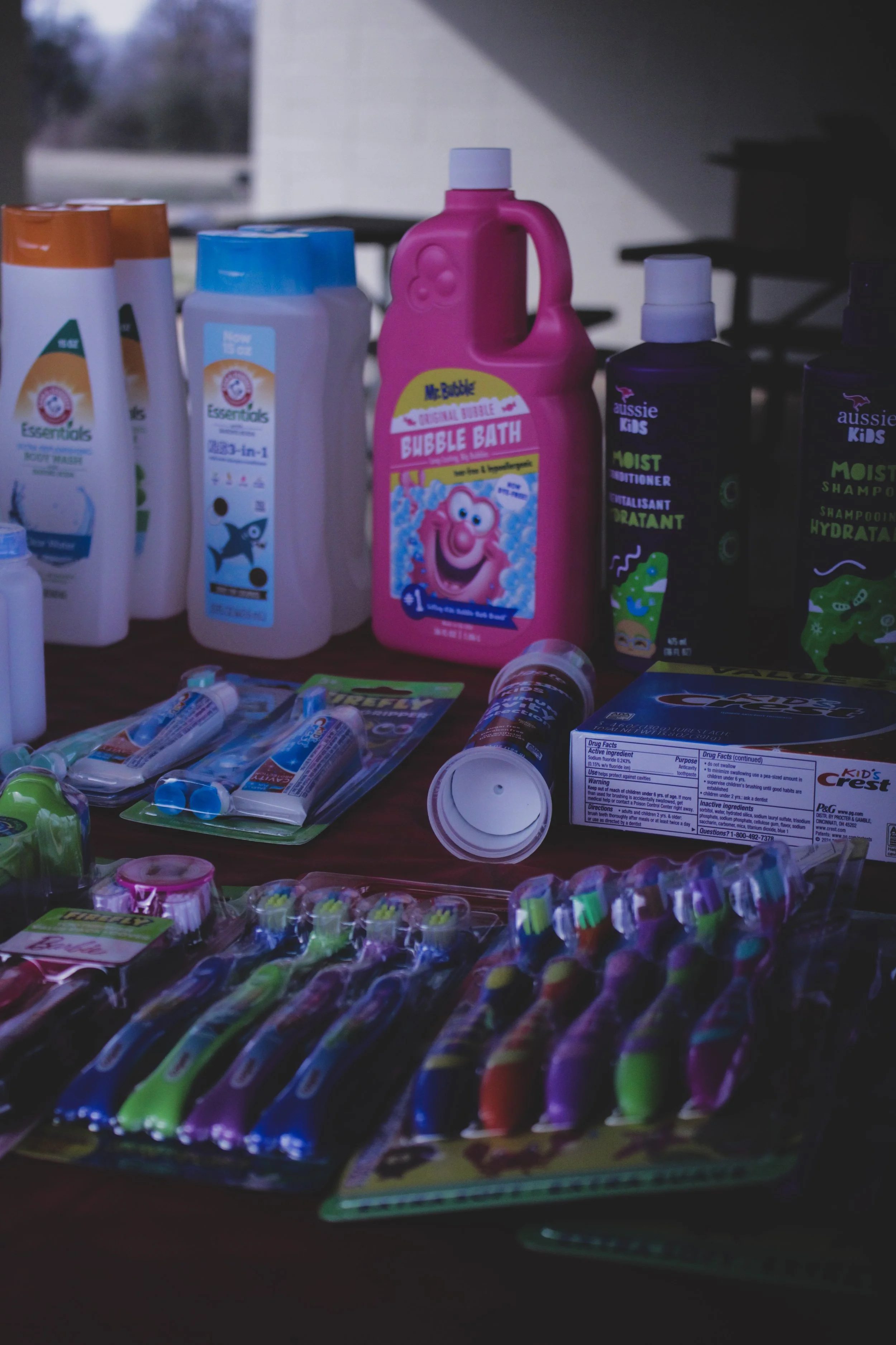 Collection of children's hygiene and dental products including bubble bath, shampoo, conditioner, toothpaste, and colorful toothbrushes.