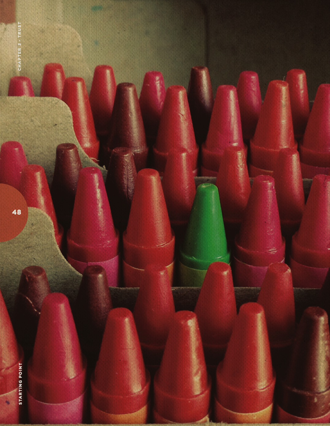 A box of red, pink, and one green crayon.