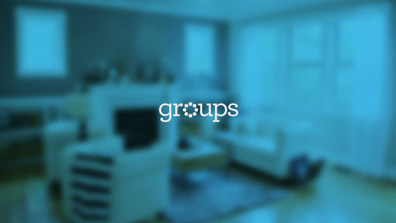 A blurred living room with couches, a television, and a fireplace with shelves above it, lit by natural light from large windows.