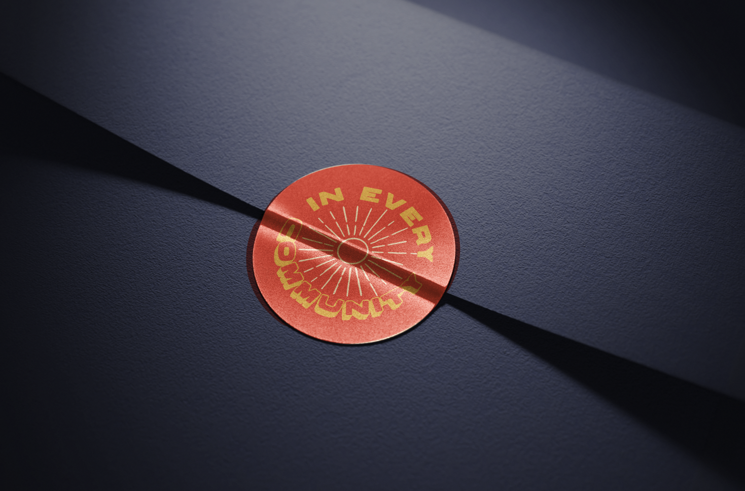 A fire alarm sticker with yellow text that reads 'In Every Emergency' on a blue wall, casting a shadow.