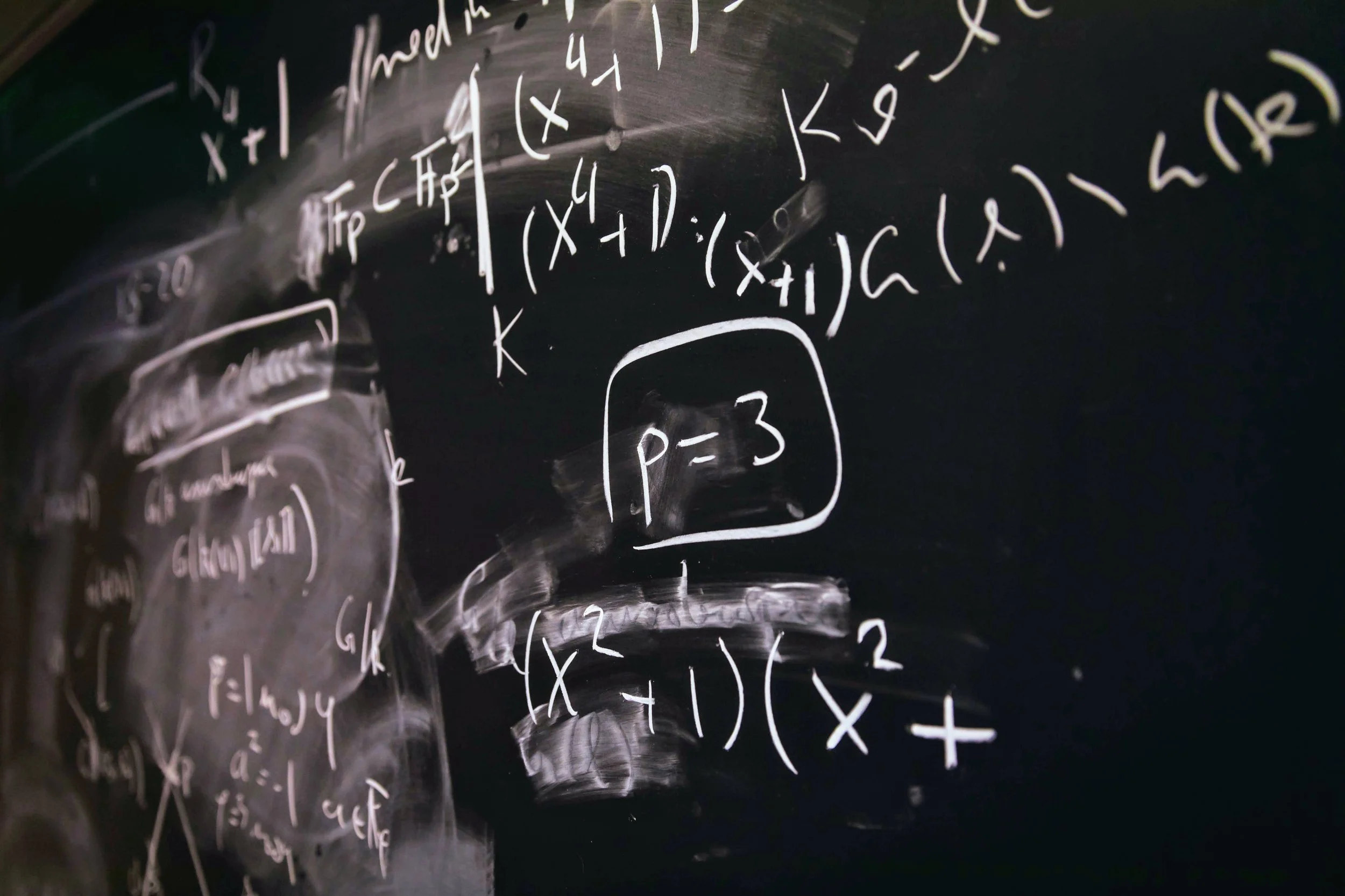 Blackboard with white handwritten mathematical equations and formulas, including a boxed notation indicating p equals 3.