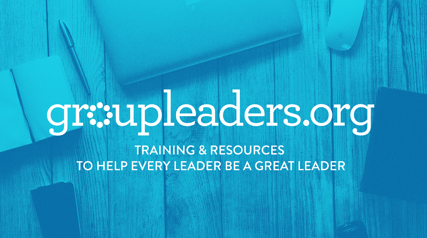 Blue overlay with the logo and text for gruppoeders.org, indicating training and resources to help leaders become great leaders, with a wooden desk, a notebook, a pen, a laptop, a coffee cup, and a smartphone in the background.