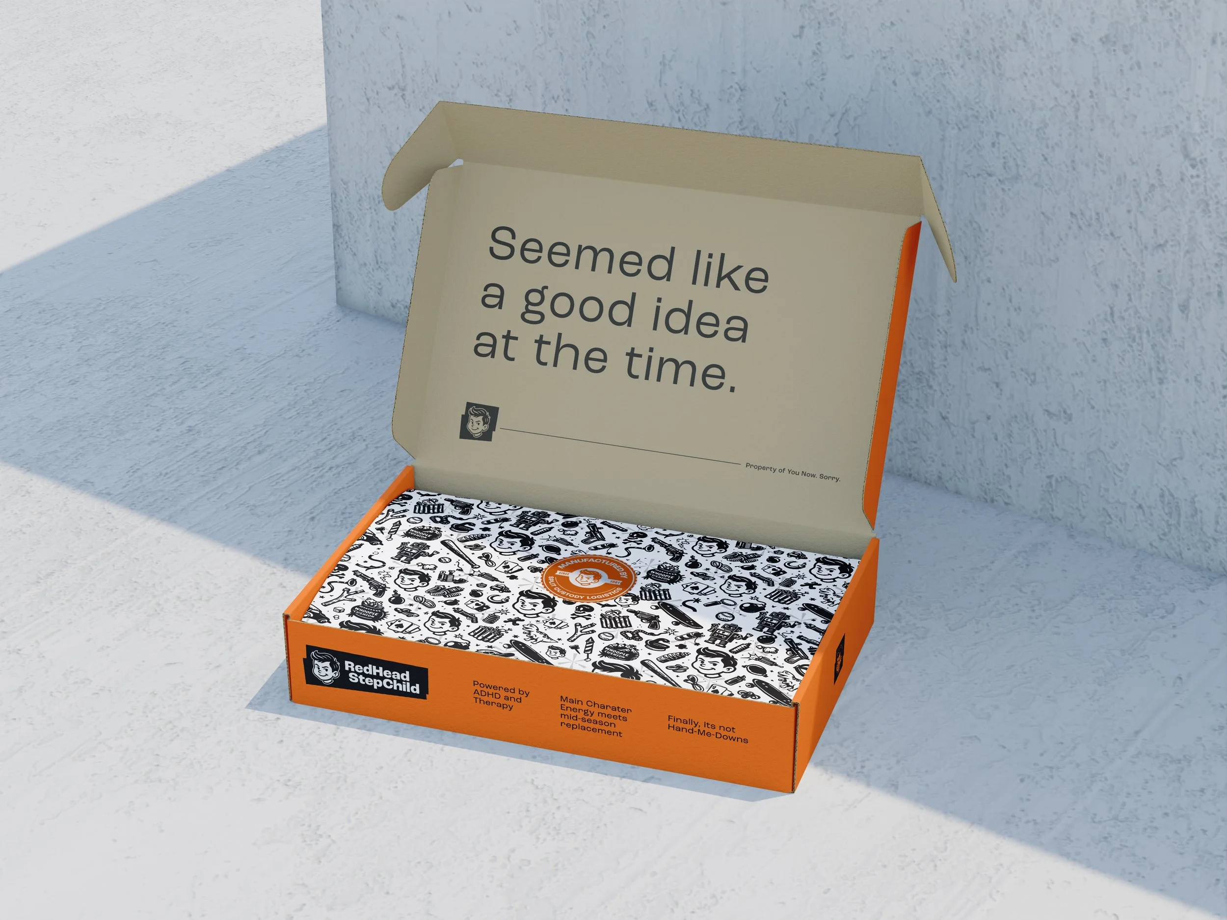 Open orange and white box with black and white patterned inner surface, displaying a card with the text 'Seemed like a good idea at the time.' and the RedHead StepChild logo.
