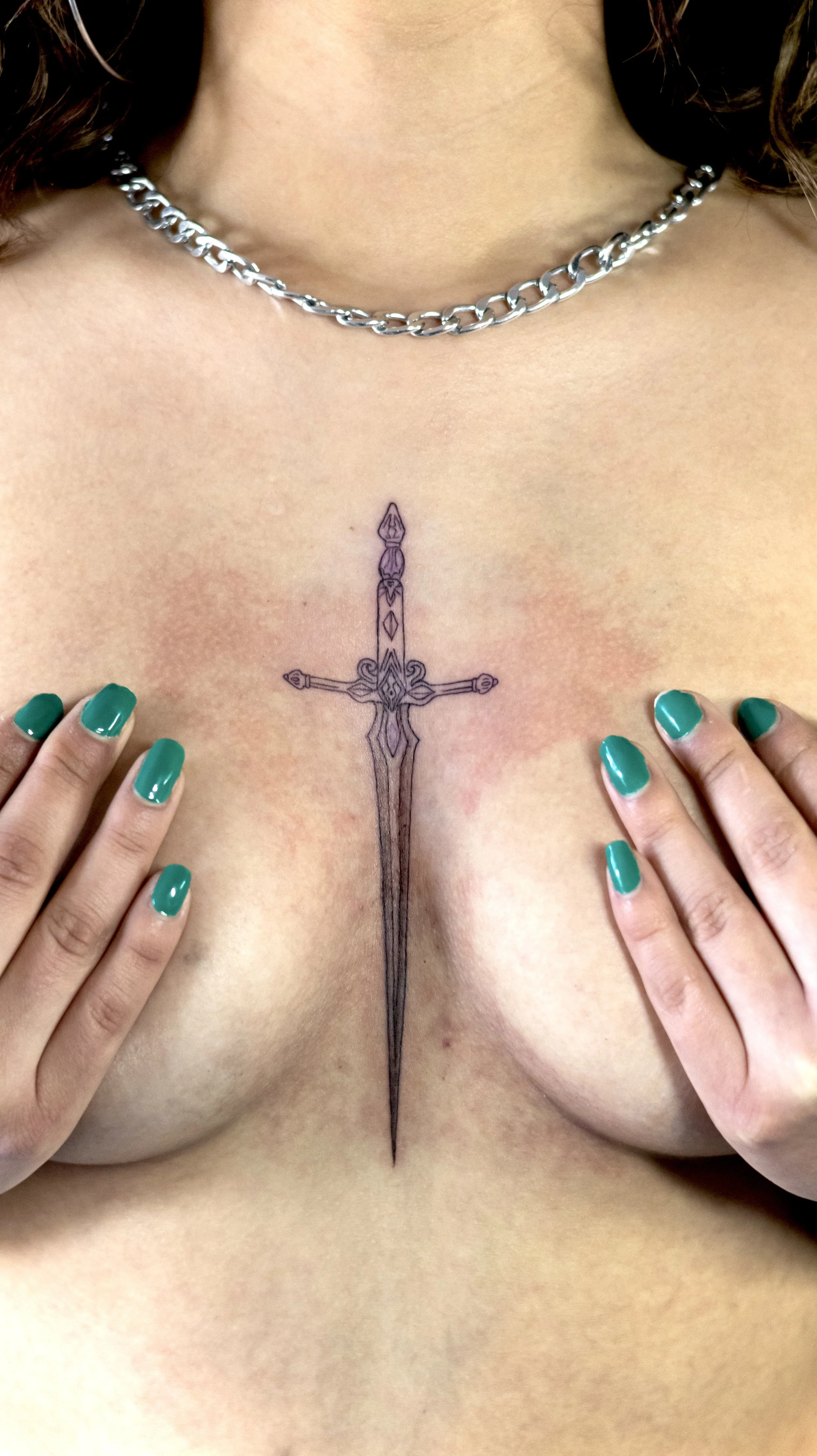 Tatuaje estilo línea fina de una espada al centro del esternón, tatuaje femenino realizado en la navaja tattoo  el mejor estudio de tatuajes en ciudad de mexico