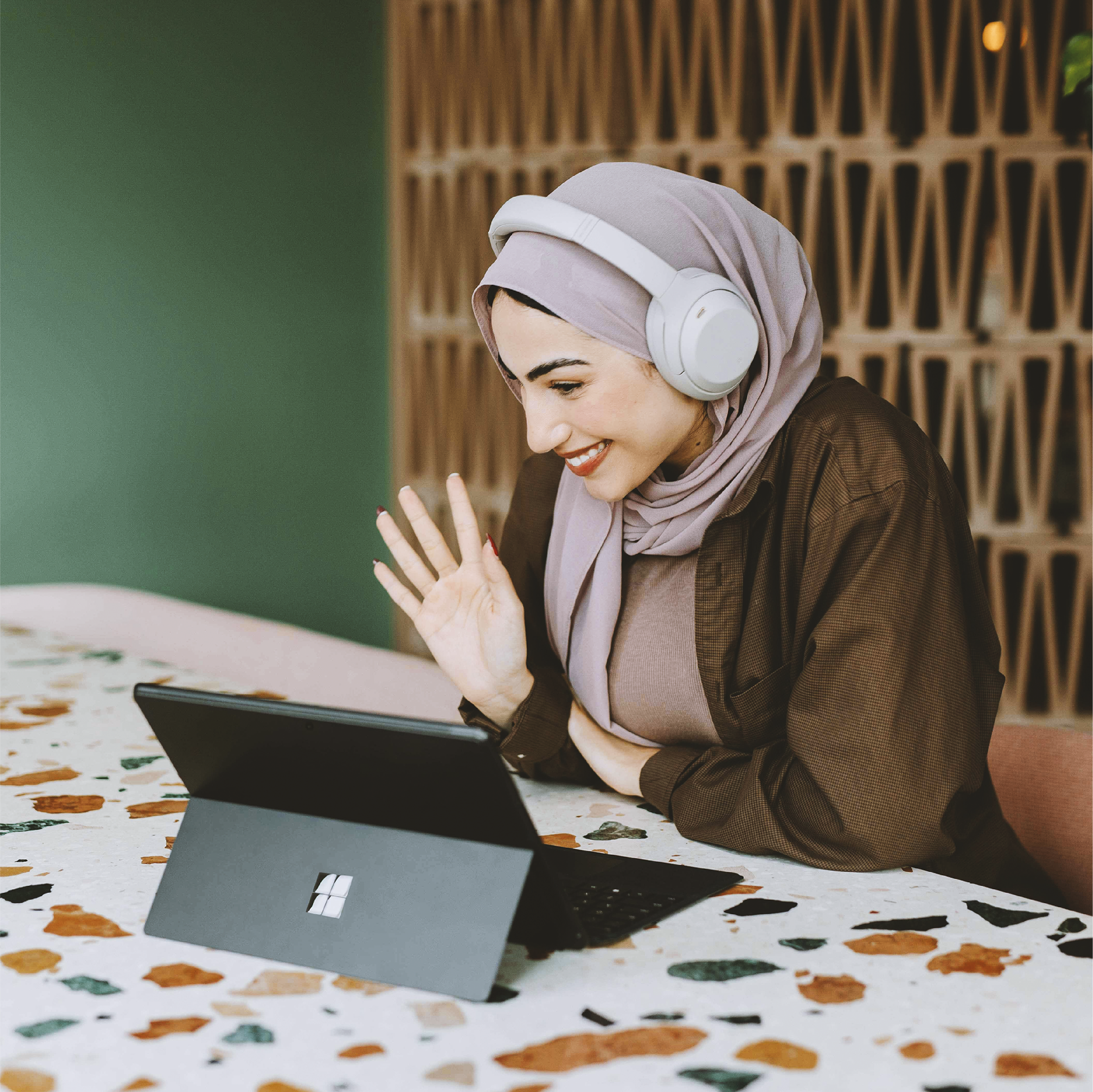 Women wearing headphones smiling and chatting on her tablet.