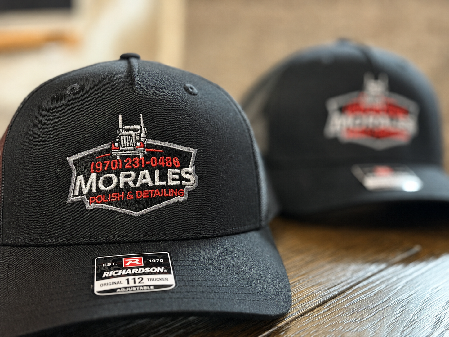 Two black baseball caps with embroidered logos for Morales Polish & Detailing.