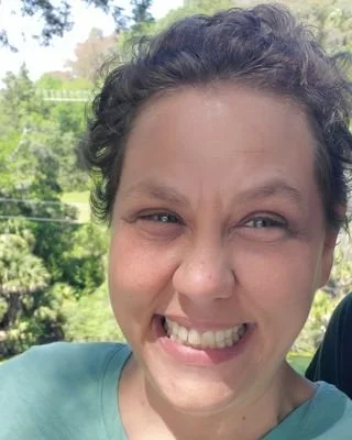 A portrait of a therapist in Florida smiling warmly and genuinely before conducting a somatic movement dance class.