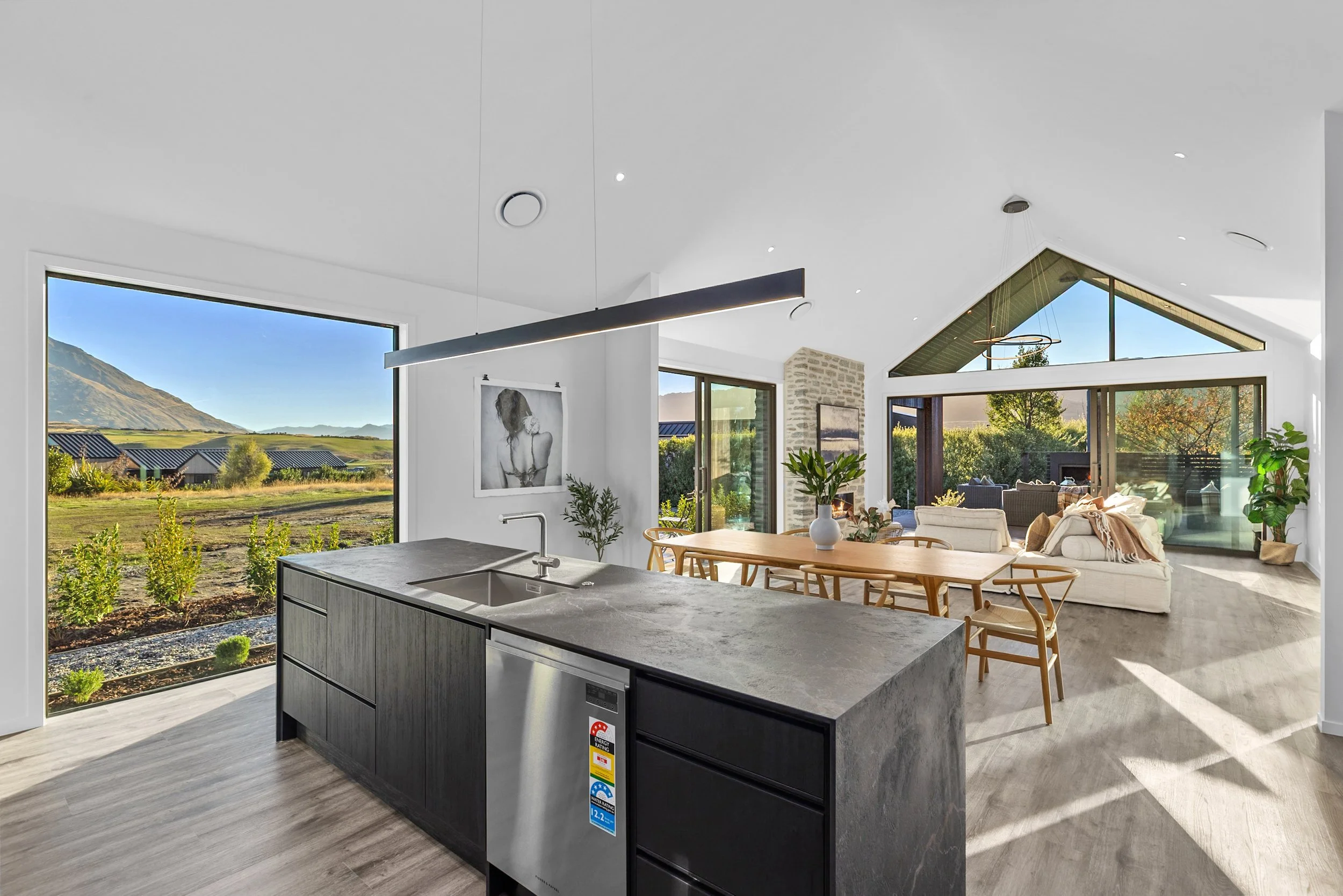 New build open-concept living room and kitchen with fireplace and scenic views — Jacks Point, Queenstown
