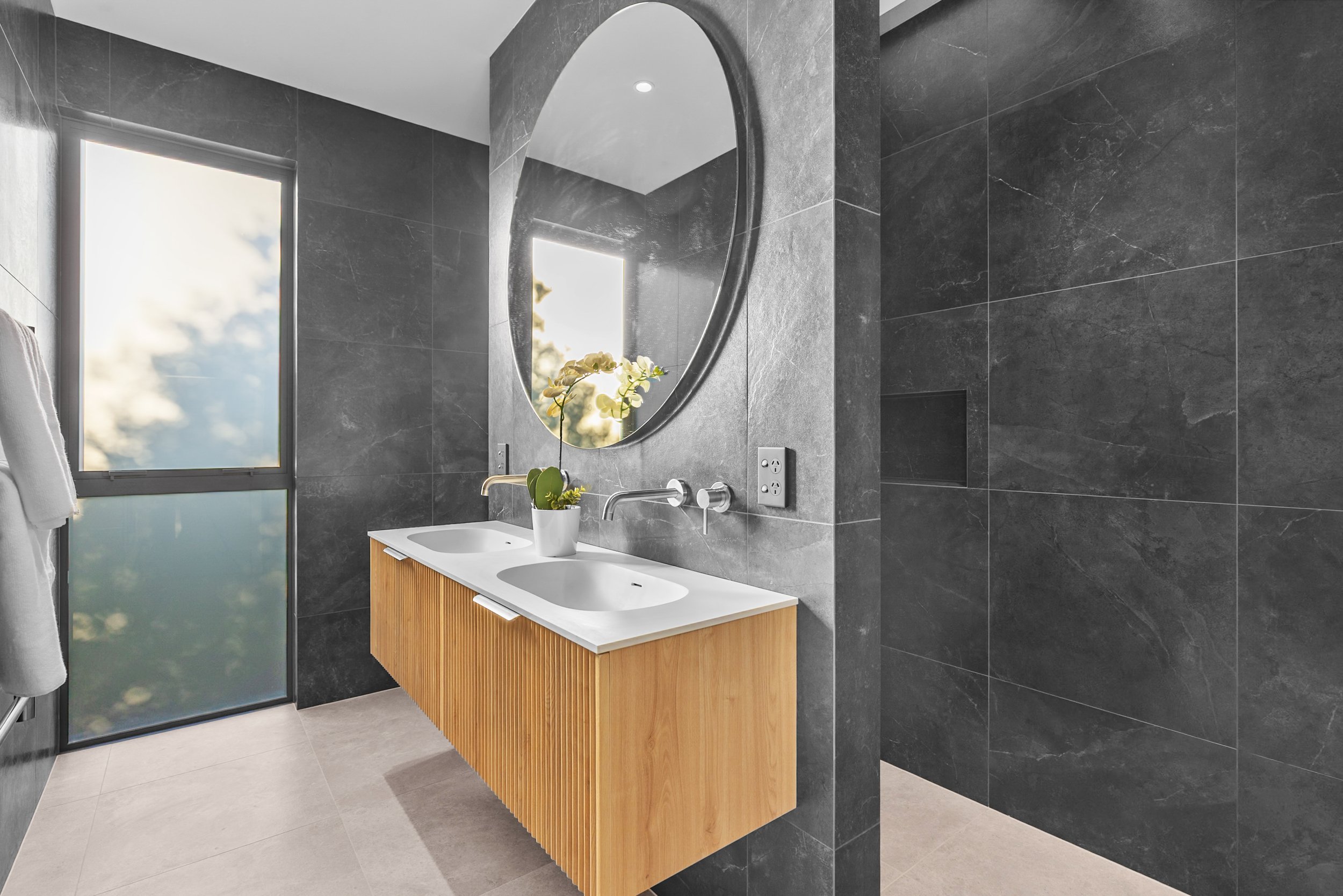 New build bathroom with dark grey tiles, wooden vanity, and frosted glass window — Jacks Point, Queenstown