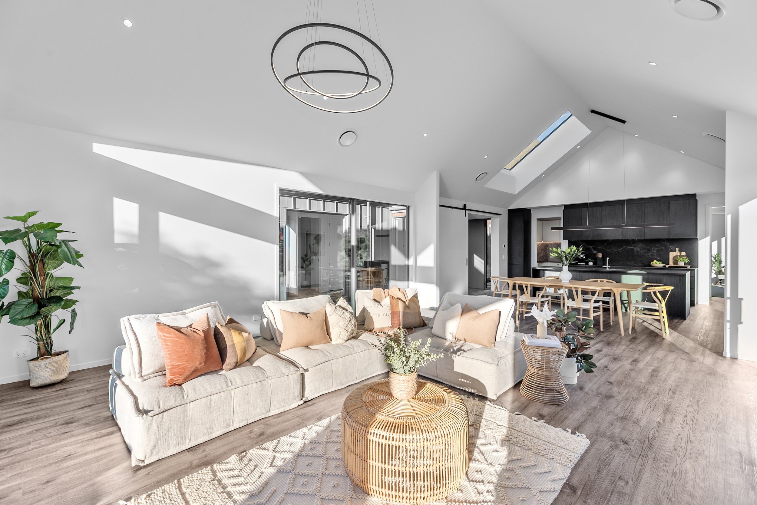 New build open-concept living room and kitchen with beige sofa, wicker coffee tables, and wooden floors — Jacks Point, Queenstown