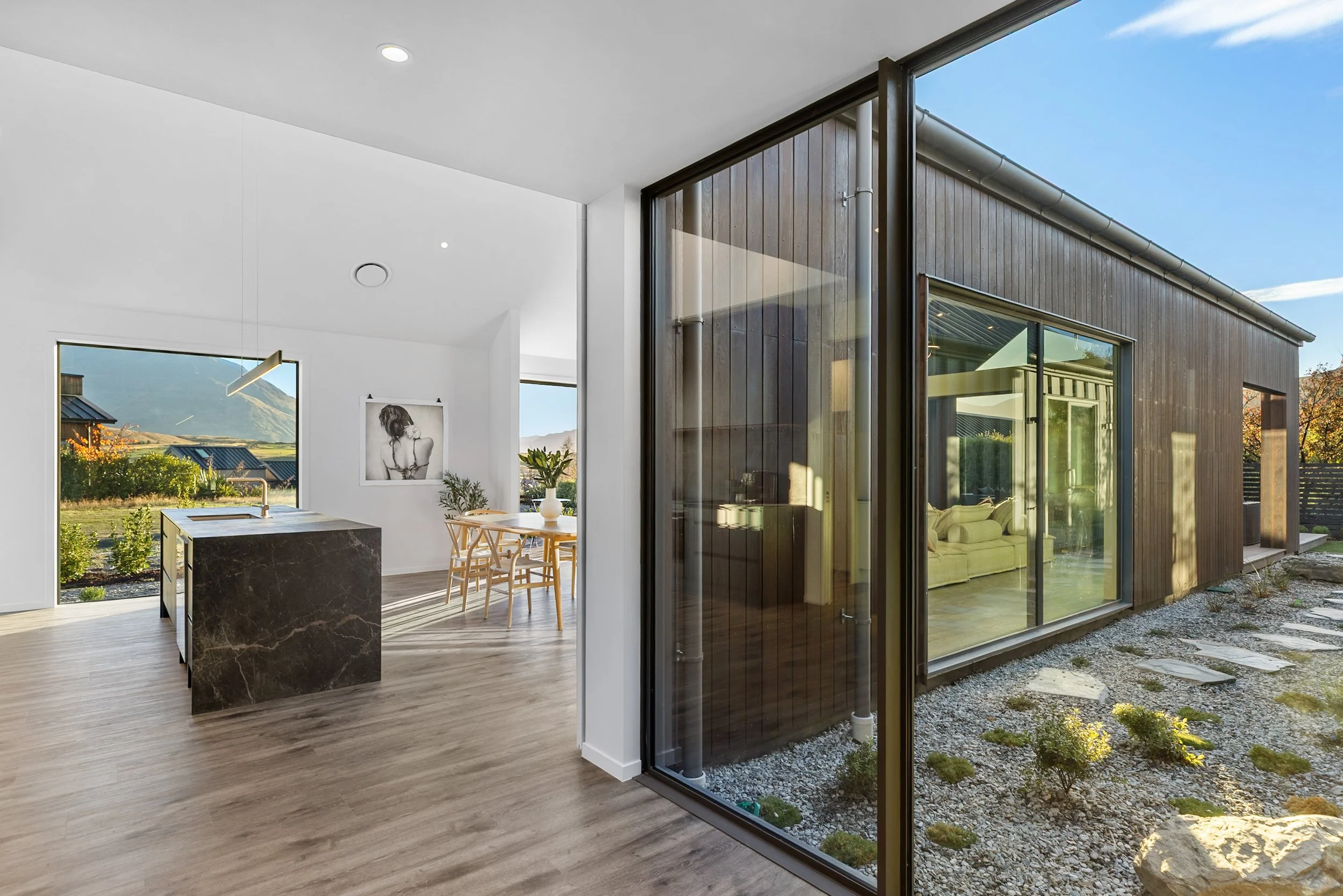 New build dining area and kitchen with sliding doors opening to landscaped yard and mountain views — Jacks Point, Queenstown