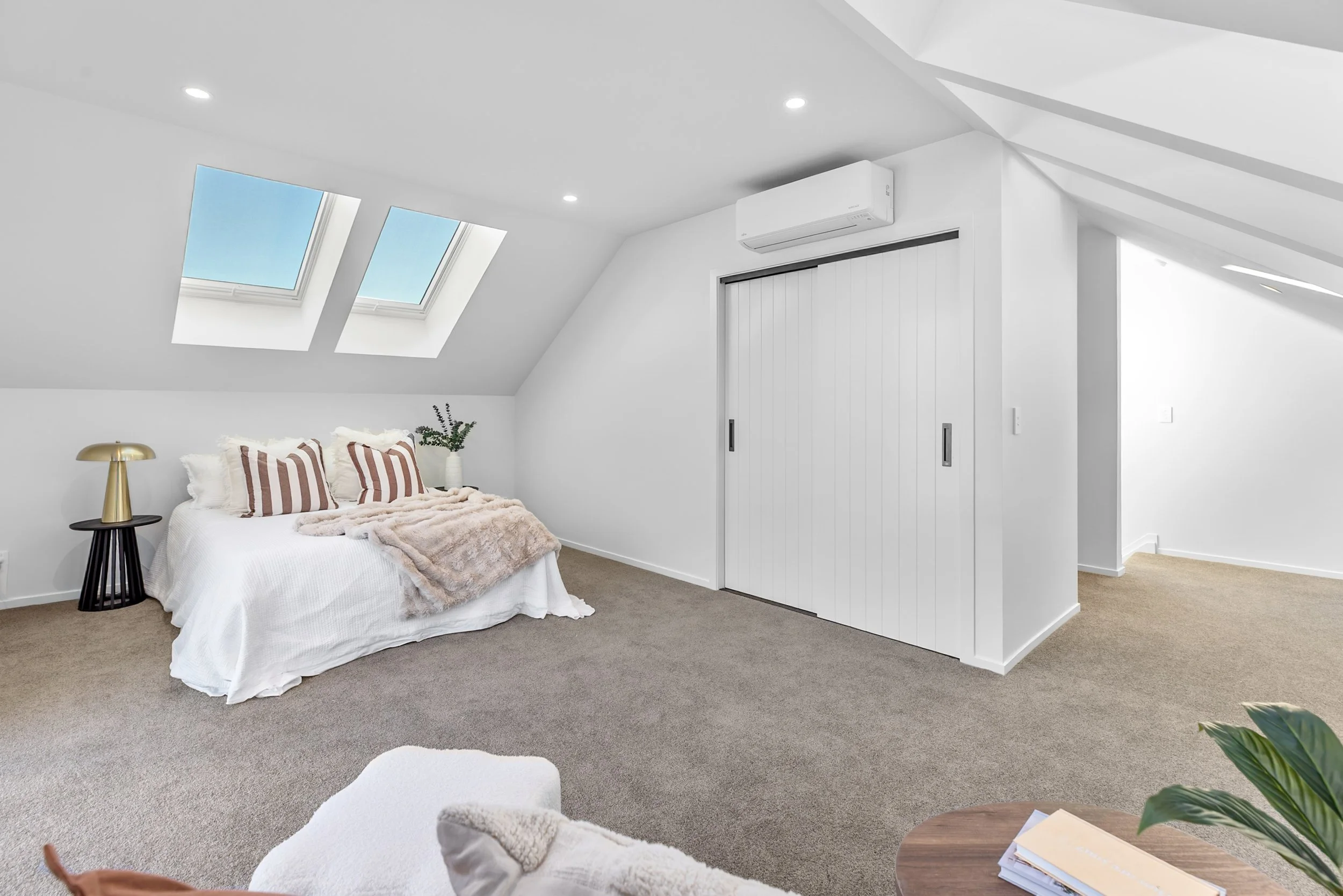 New build bedroom with skylight windows, striped pillows, and gold lamp accent — Jacks Point, Queenstown