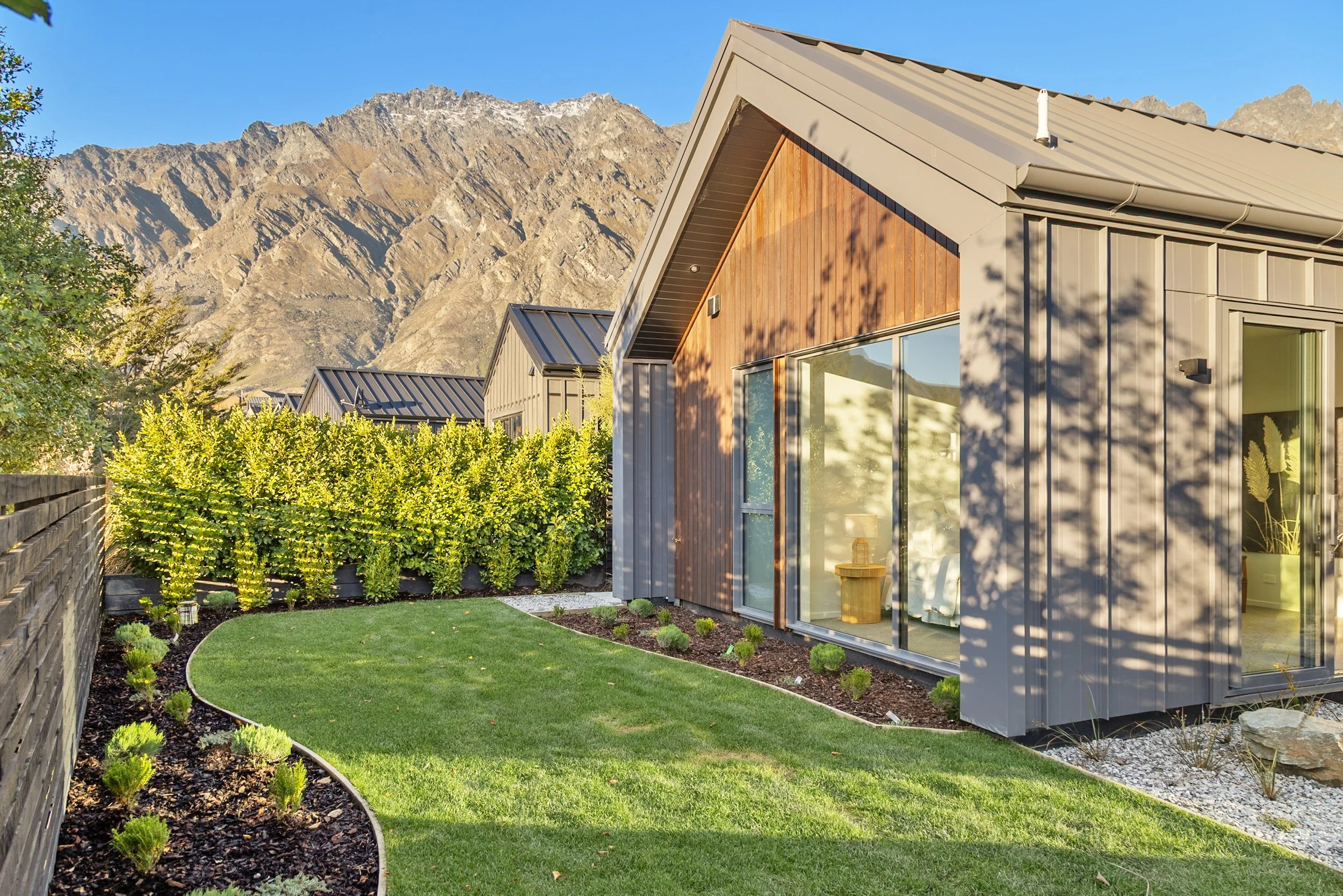 New build with metal roof and timber exterior, sliding glass doors and lawn — Jacks Point, Queenstown