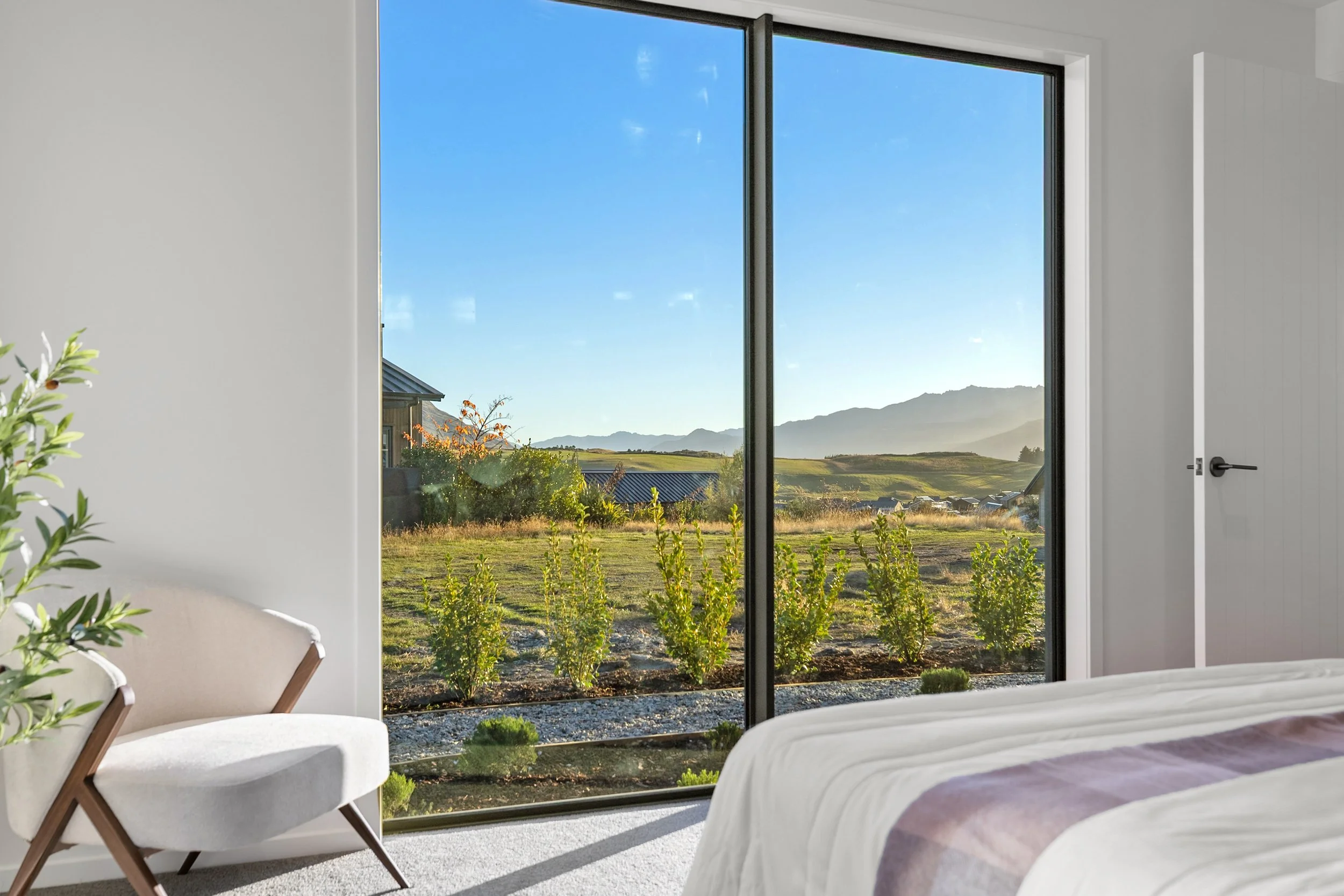 New build bedroom with sliding glass doors opening to fields and mountain views — Jacks Point, Queenstown