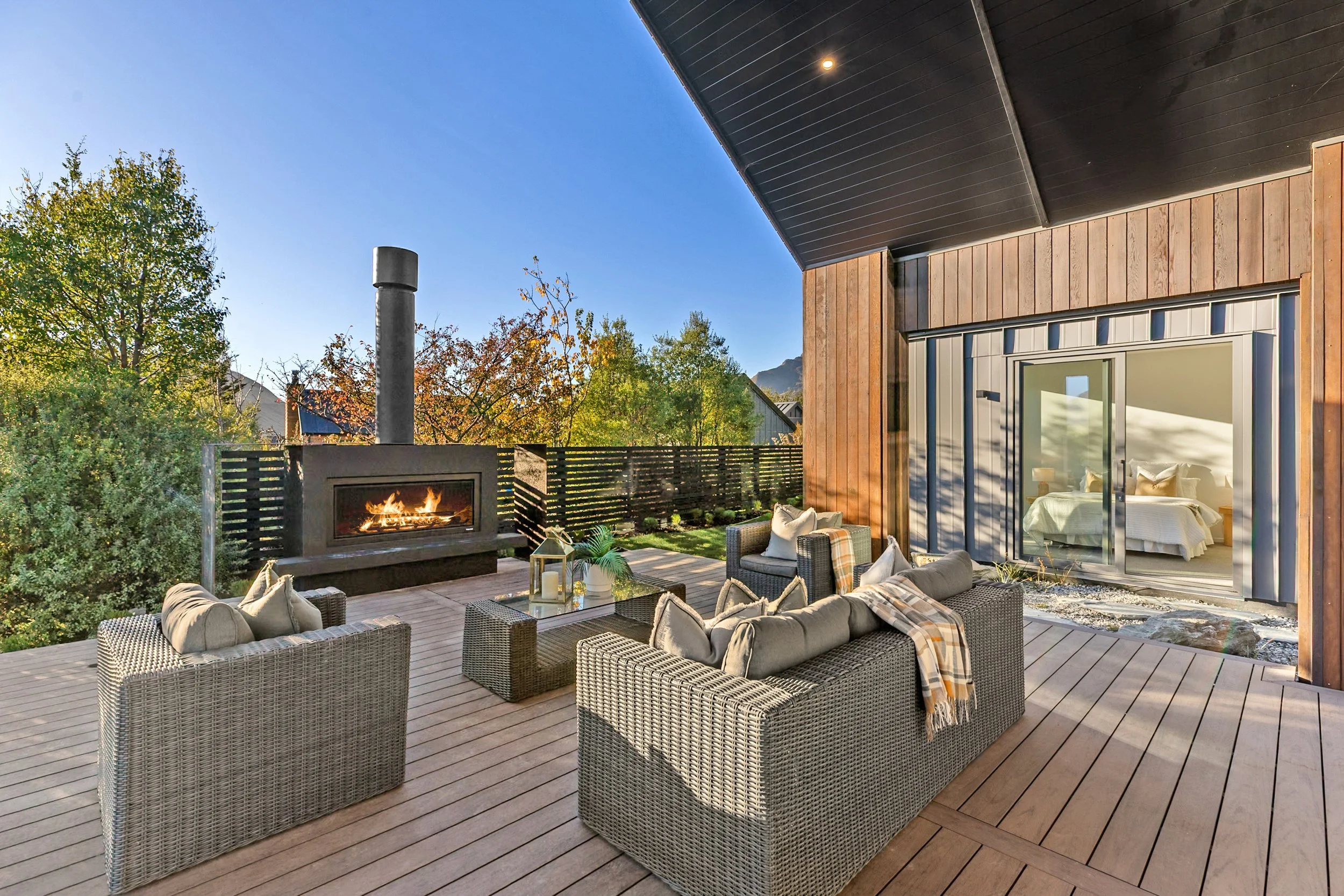 New build daytime patio with fire pit and sliding door to bedroom, mountain backdrop — Jacks Point, Queenstown