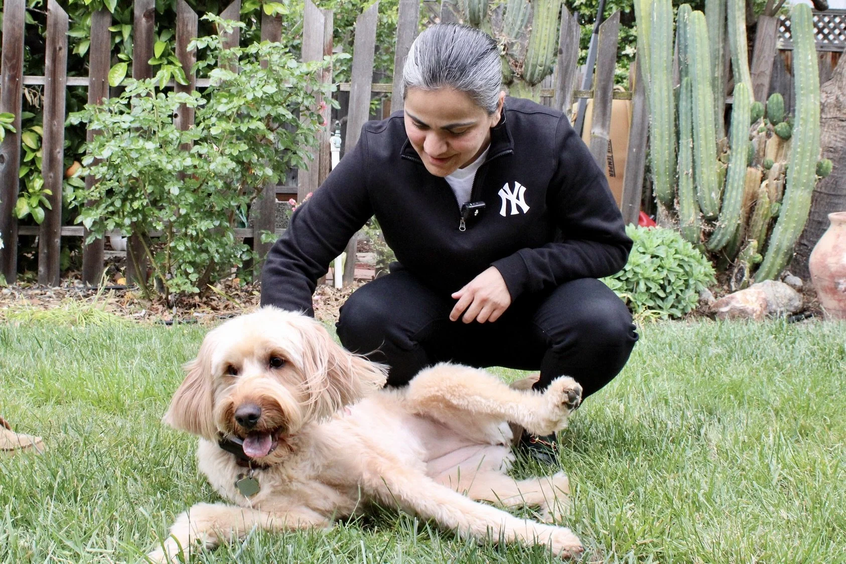 Aisha Wahab petting a tan medium sized dog.