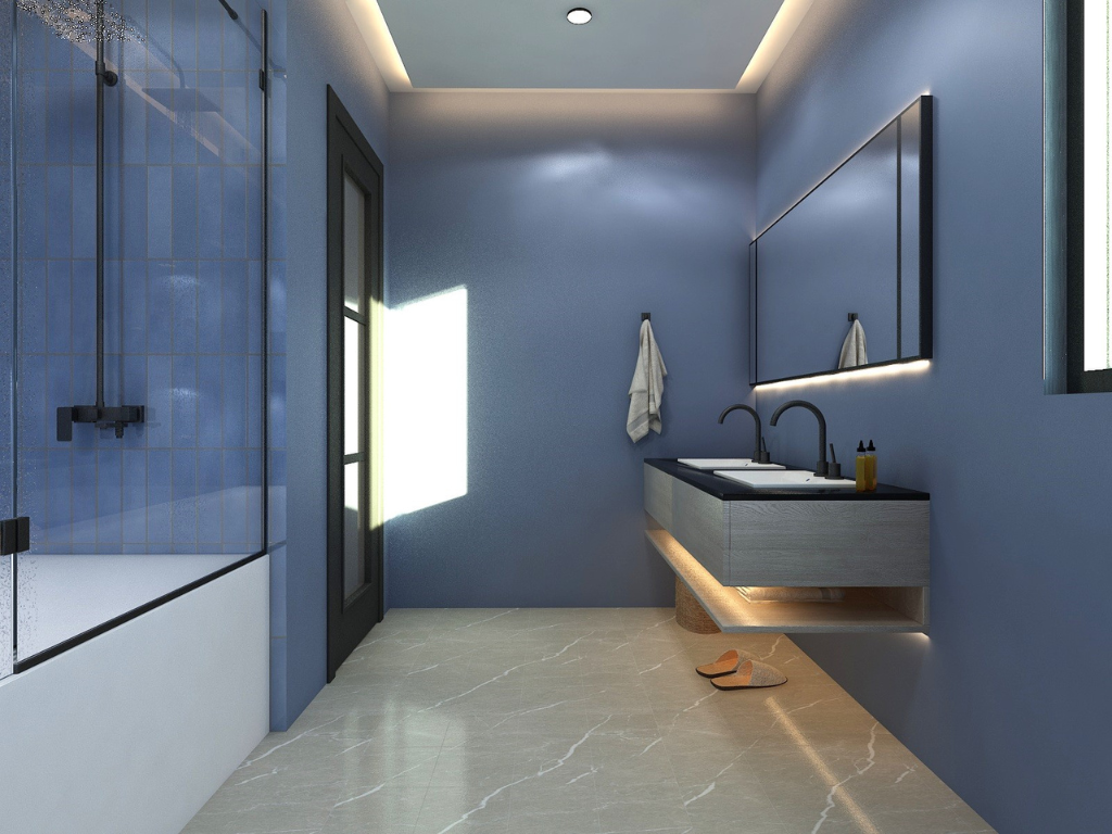 Modern bathroom with blue walls, walk-in shower with glass doors, floating wooden vanity with double sinks, large mirror with backlighting, and beige marble floor.