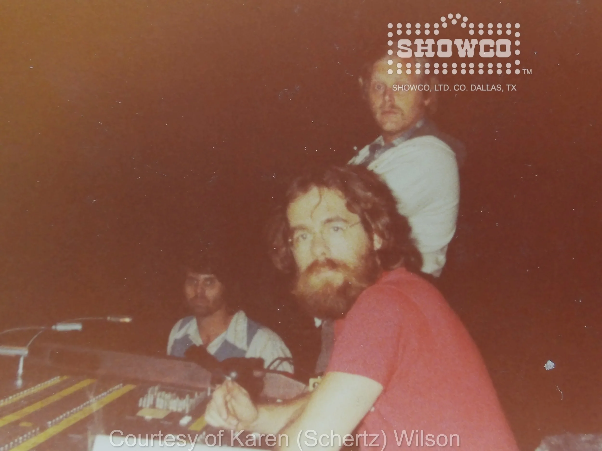 Showco alumnus Buddy “Budrock” Prewitt seated at a control console, wearing a red shirt.