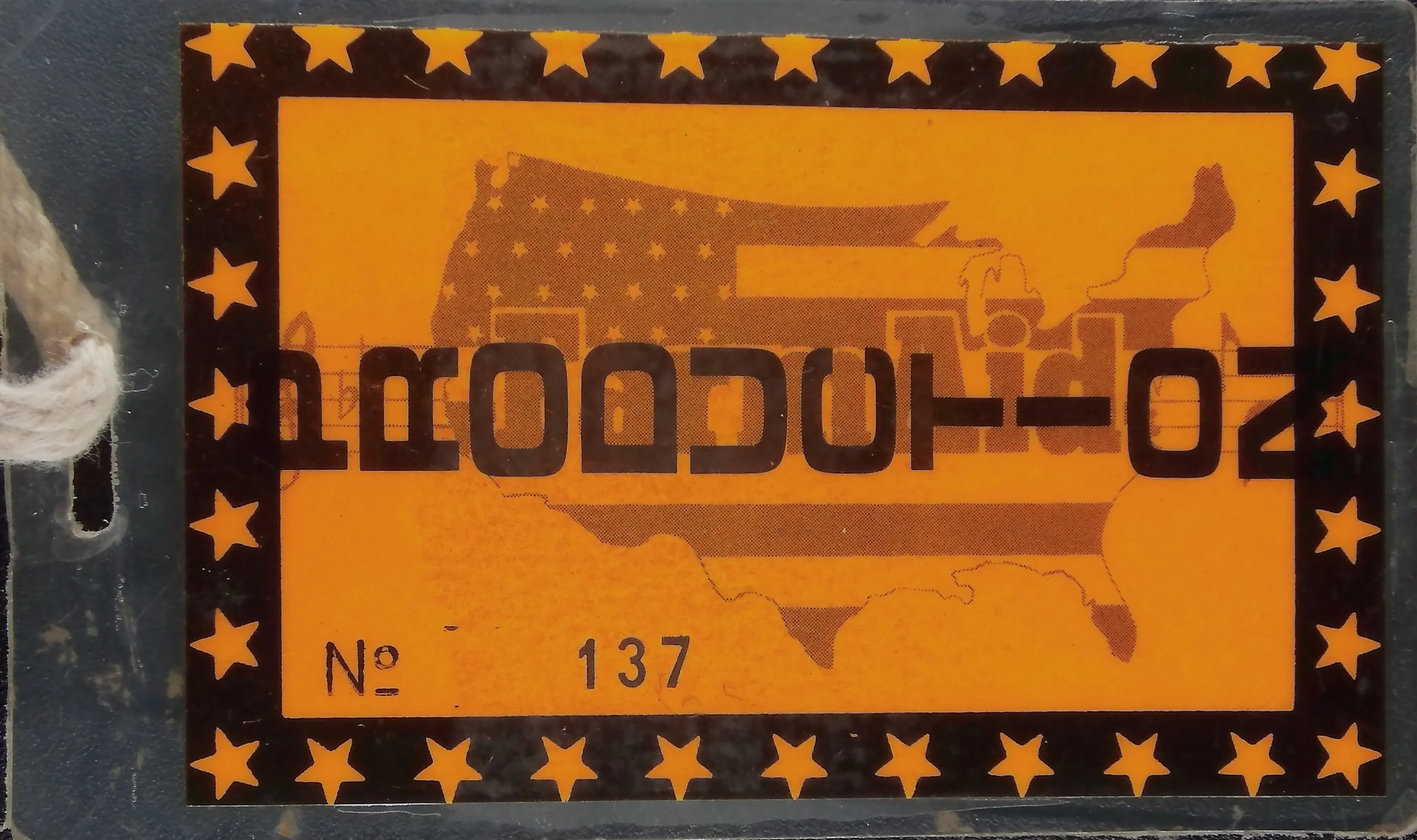 Farm Aid production laminate, no. 137, with an orange-and-black design, star border, and U.S. map motif.