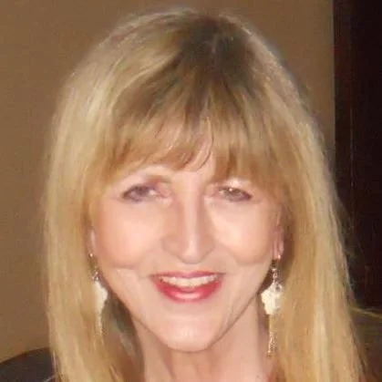 A smiling middle-aged woman with blonde hair, wearing earrings and red lipstick.