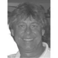 A black and white photo of a smiling person with medium-length, wavy hair.