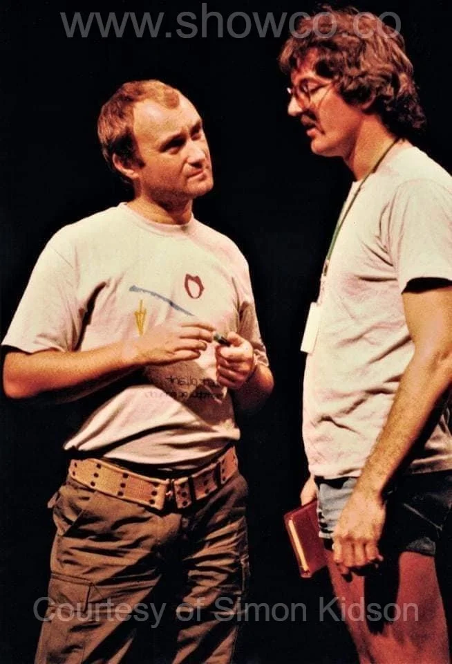 Phil Collins in POM shirt speaking with Mike KIdson