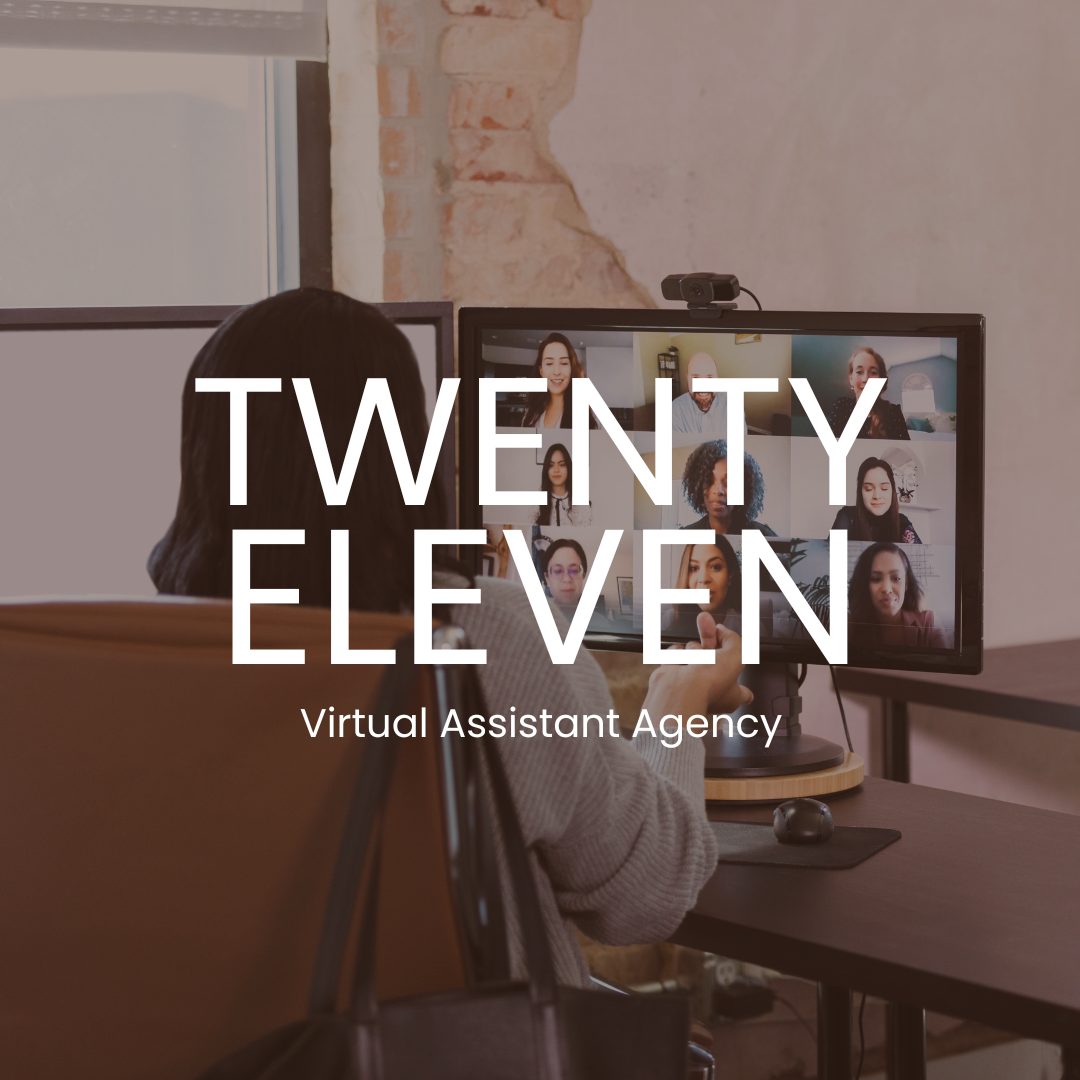 A woman sitting at a desk during a video conference call on a computer monitor with multiple participants, in a room with exposed brick wall.