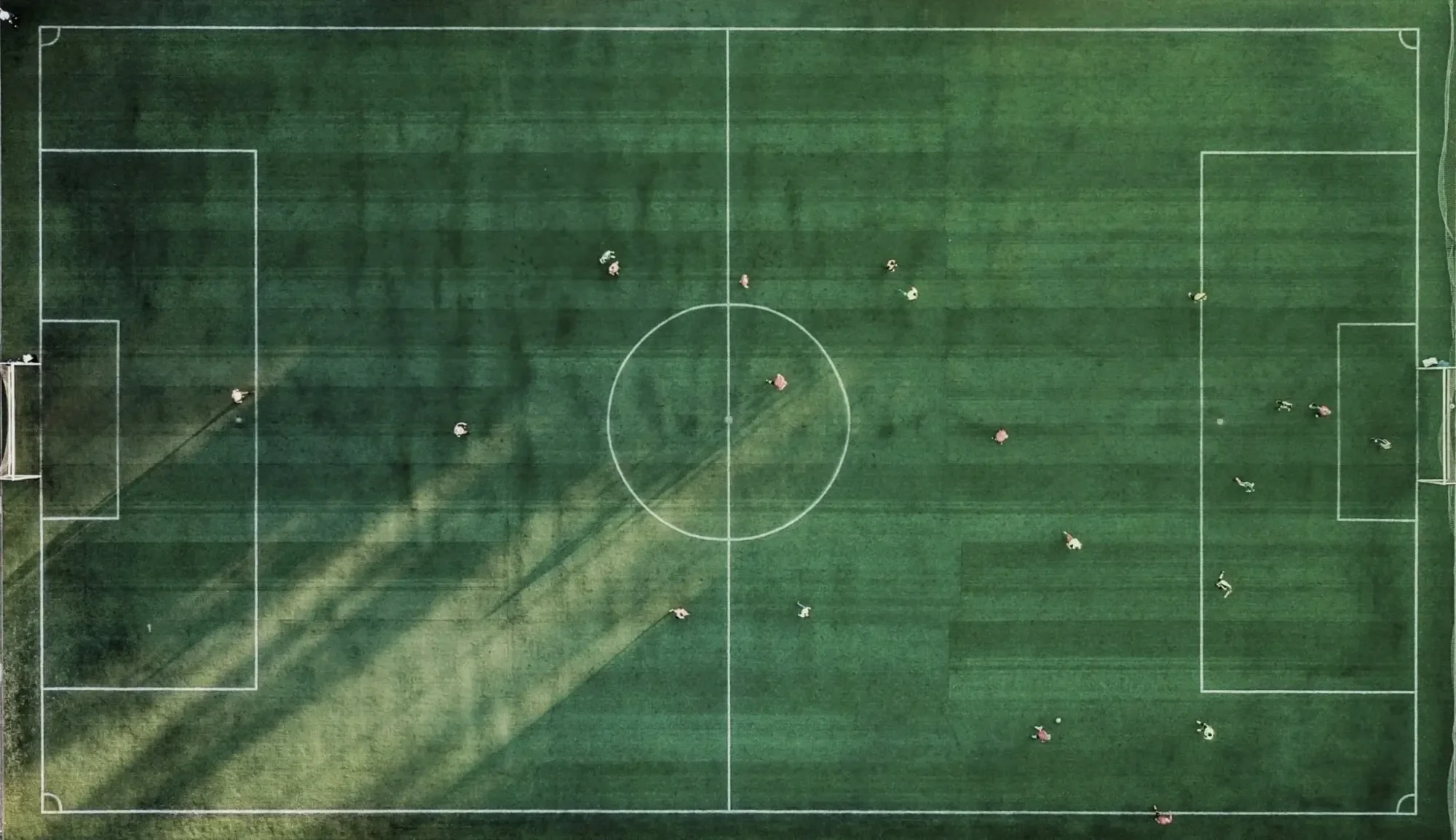 An aerial view of a soccer field during a practice session with players scattered around the field.