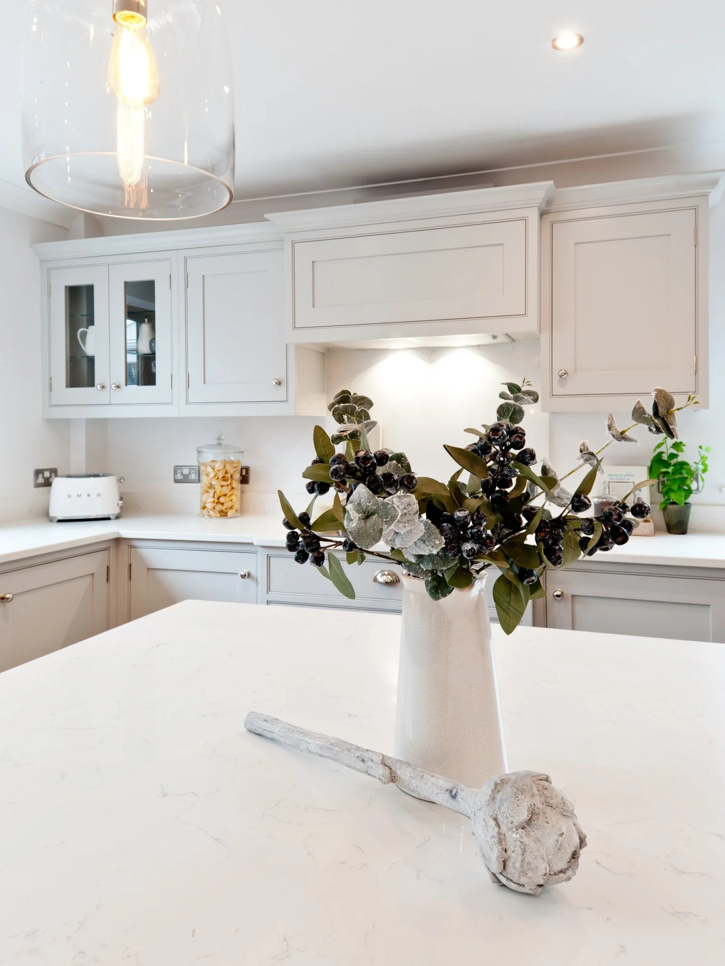 A perfect example of a wintry kitchen.

A few winter leaves on the island, warm lighting overhead, and cool palleted cabinetry that is pretty enough on its own but also creates a canvas for seasonal style.

A simple Shaker is style that adapts quietl