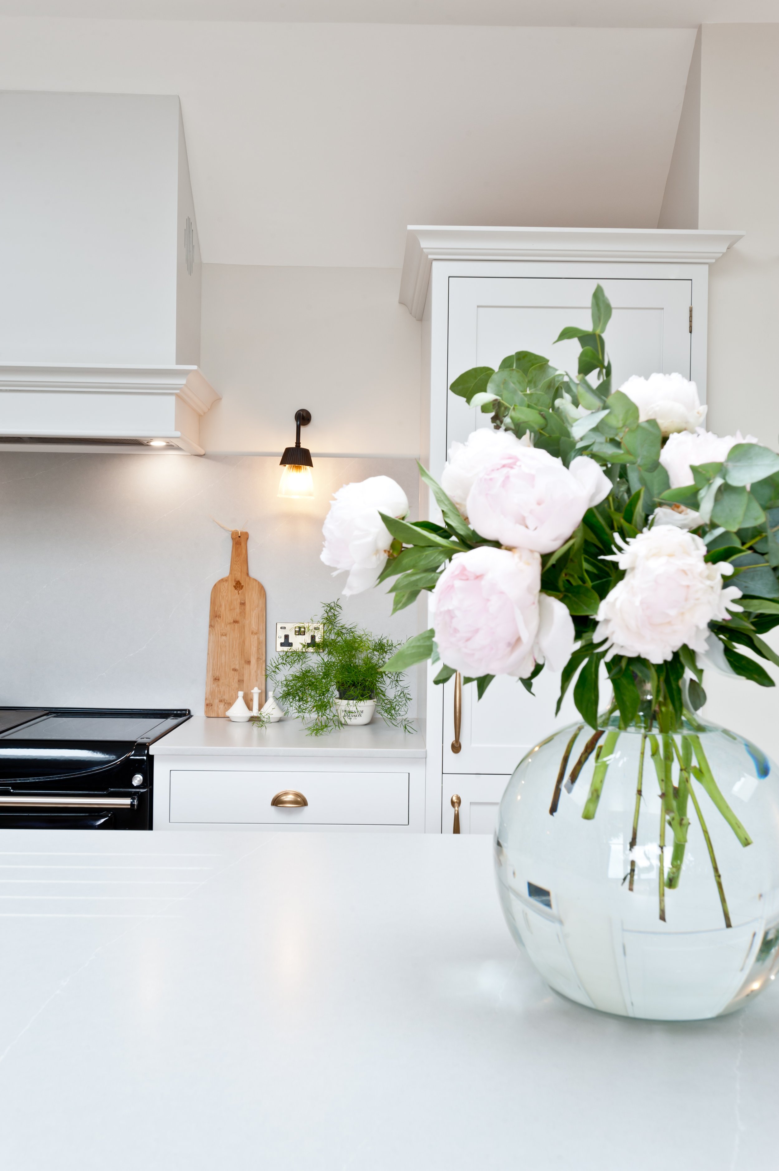 Bespoke Shaker kitchen with painted island, tall fitted cabinetry, quartz surfaces and brass hardware.