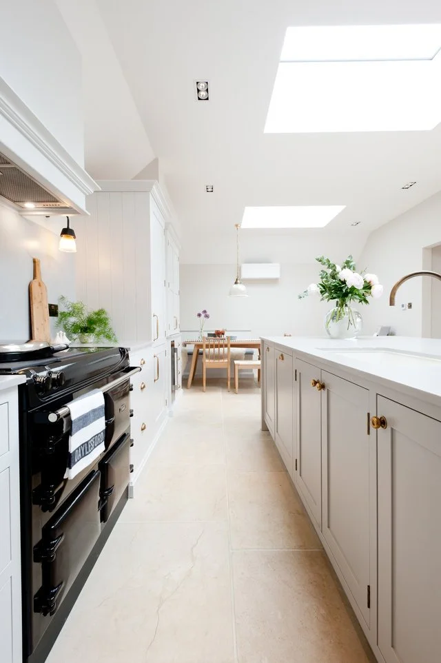 Painted bespoke kitchen island with quartz worktop, fitted cabinetry and integrated cooking appliances.