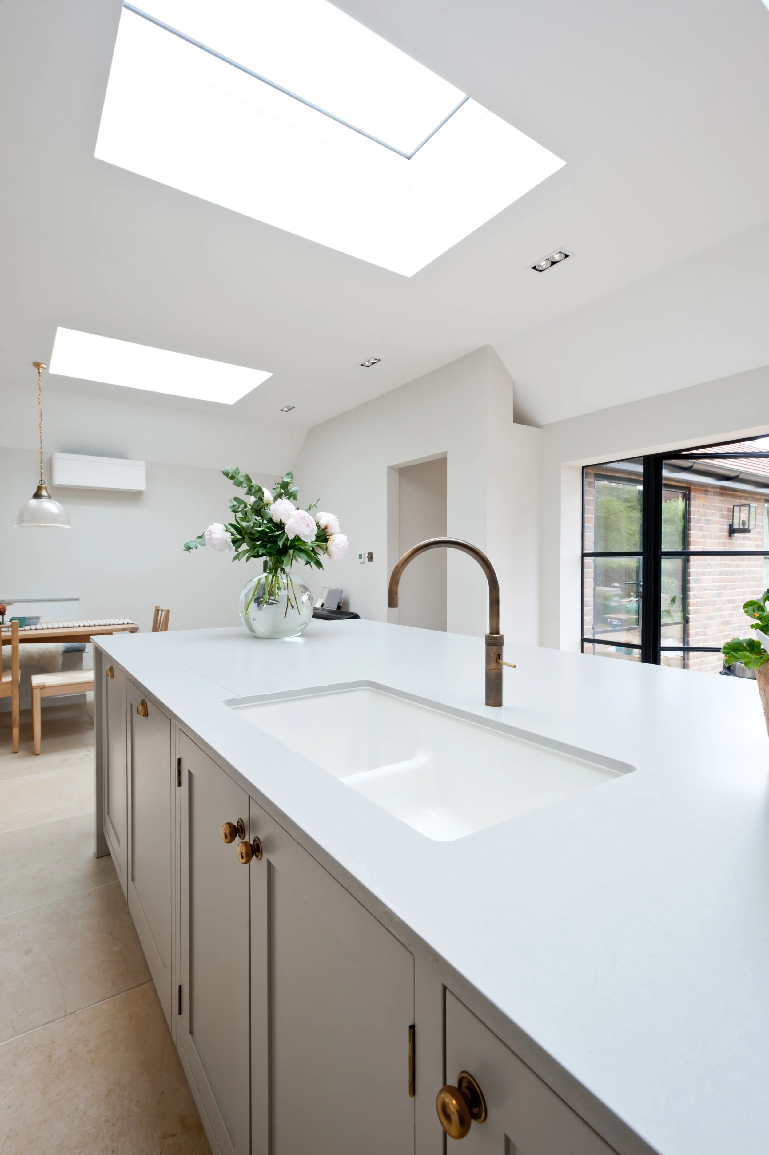 Bespoke Shaker kitchen island with integrated sink, quartz worktop and views through the light-filled kitchen.