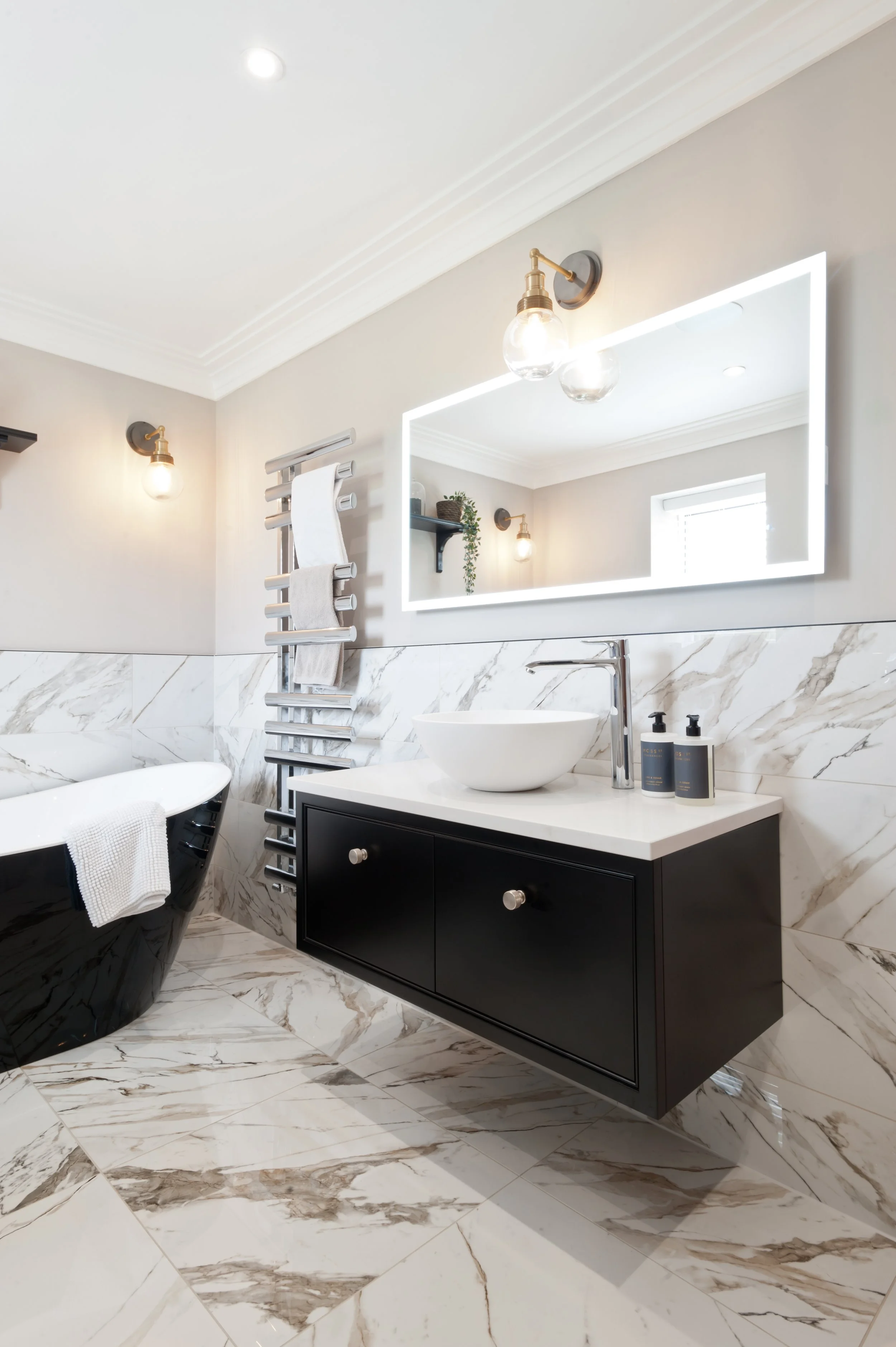 Black, white and beautifully bespoke. Made-to-measure bathroom furniture brings a tailored finish to this marble-clad space.