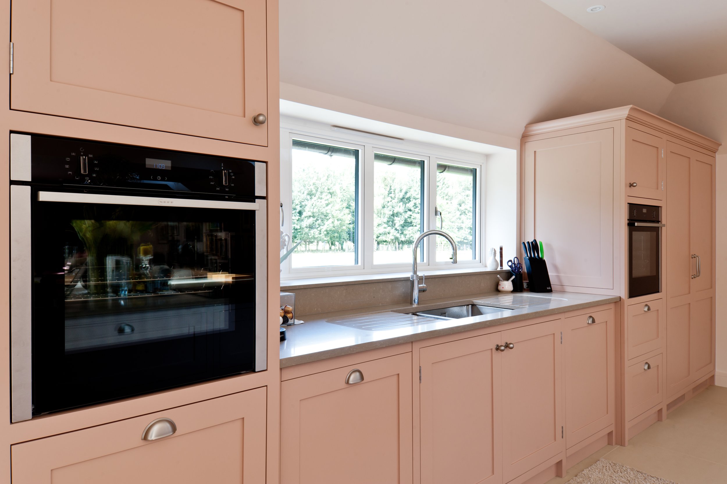 Bespoke kitchen cabinetry with integrated ovens, stone worktops and painted shaker-style doors.