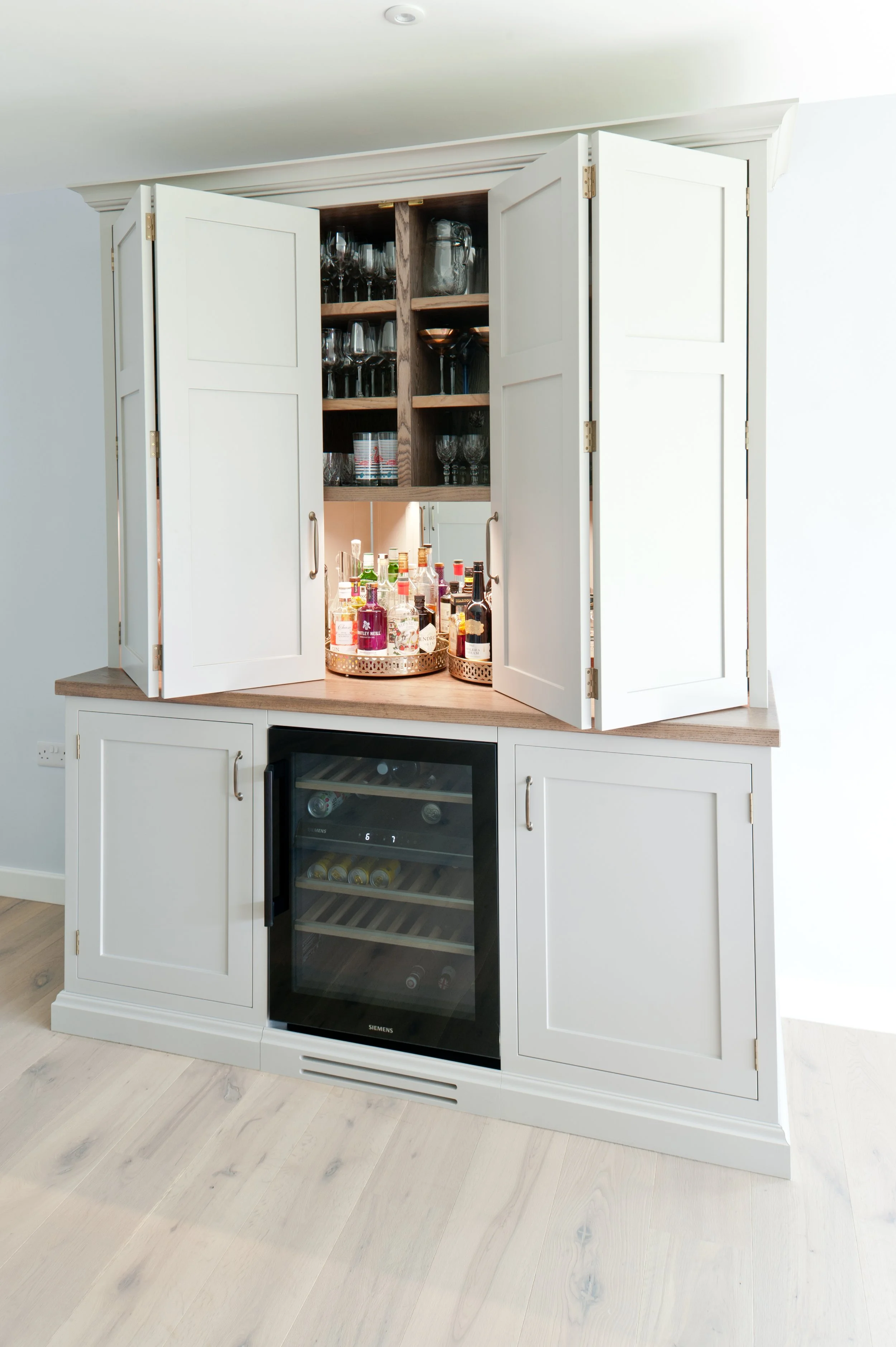 Now you see it… A concealed bespoke home bar with integrated wine cooler, drinks storage and doors that close it all neatly away.