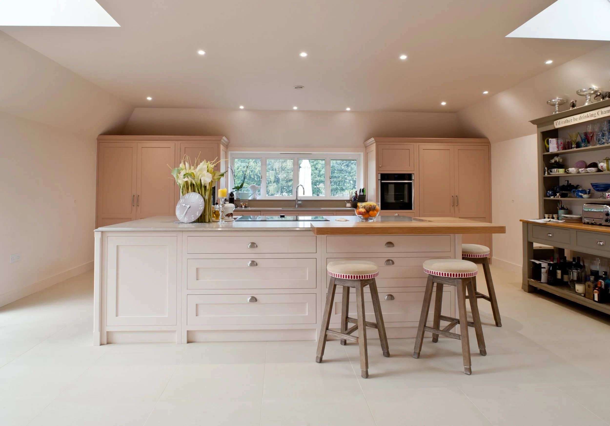 Painted bespoke kitchen cabinetry with central island, integrated appliances and oak flooring.