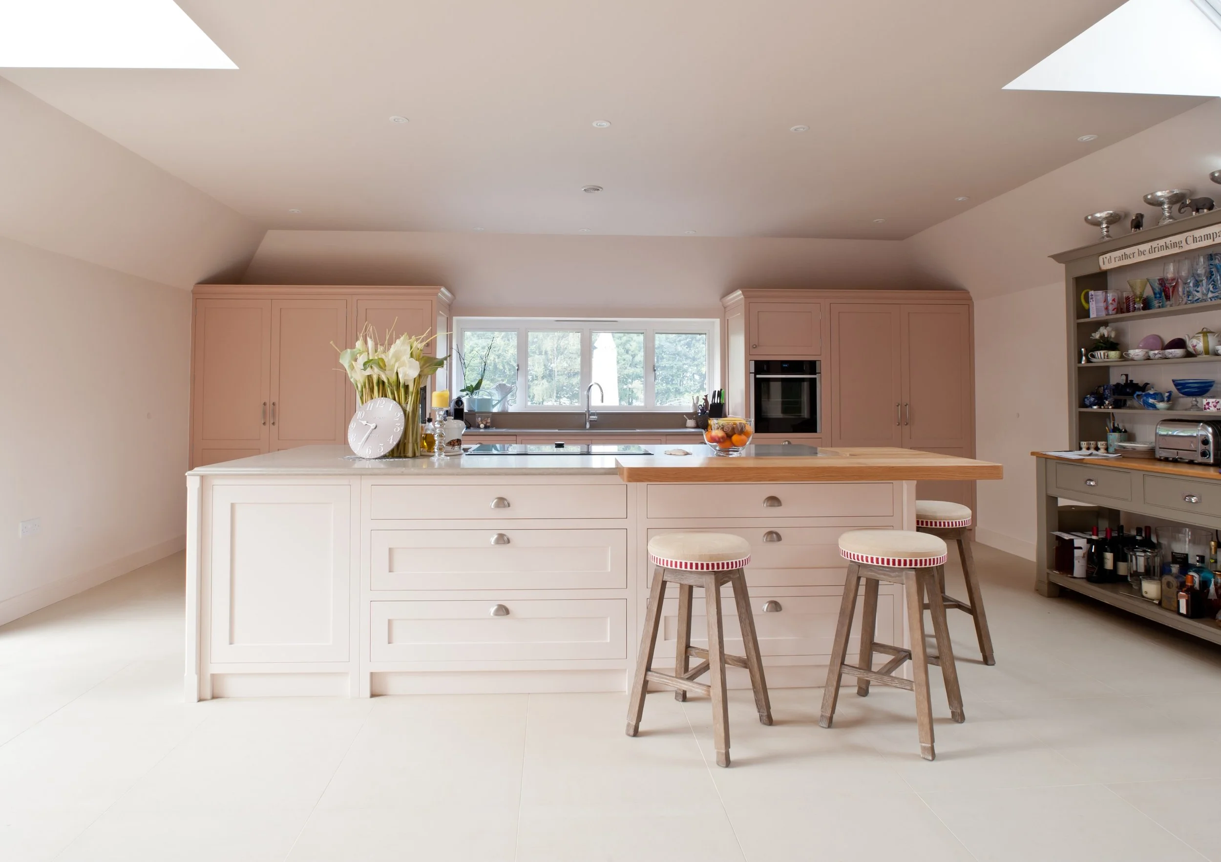 Bespoke kitchen island with painted cabinetry, timber worktop detail and upholstered bar stools.