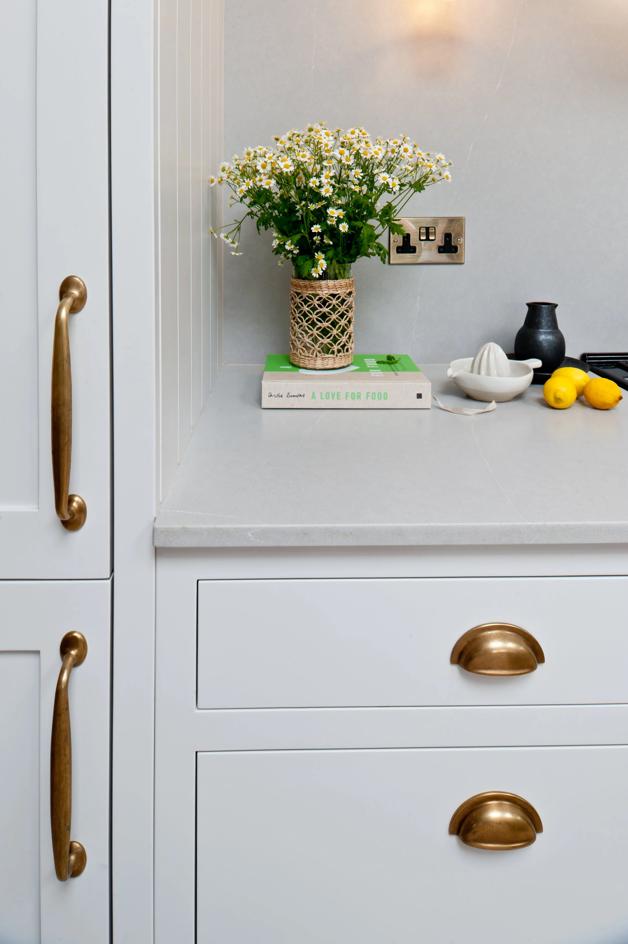 Close-up of handcrafted Shaker cabinetry with traditional frame detailing and warm brass cup and pull handles.