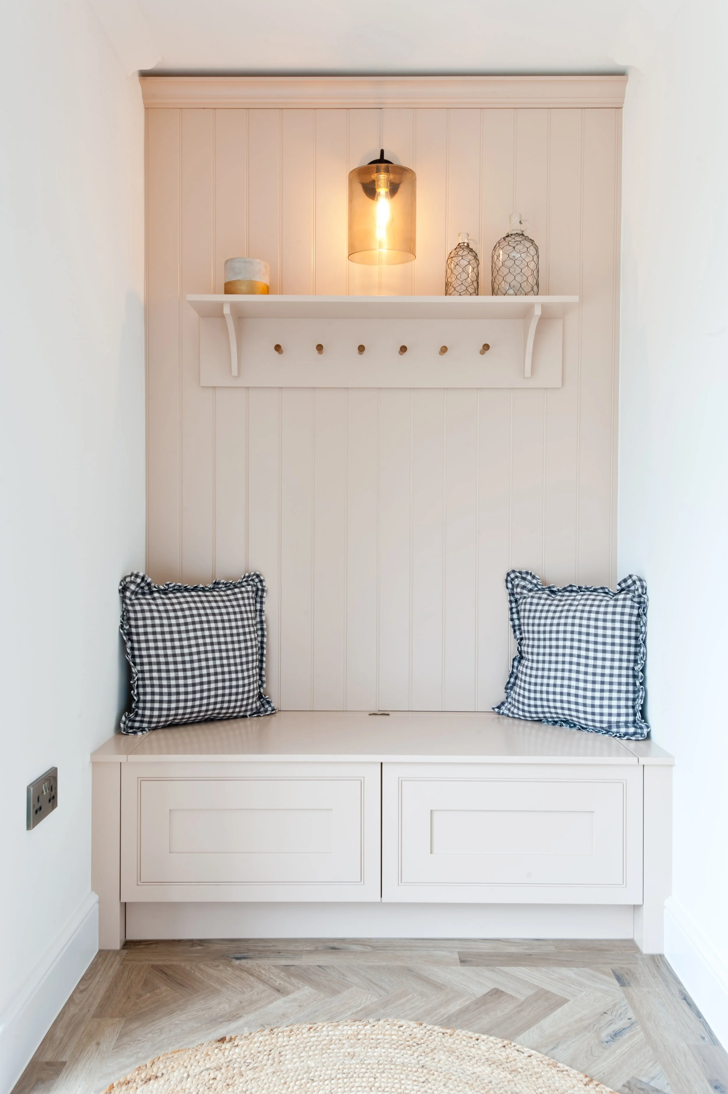 Bespoke boot room bench with concealed drawer storage, painted tongue-and-groove panelling and checked cushions.