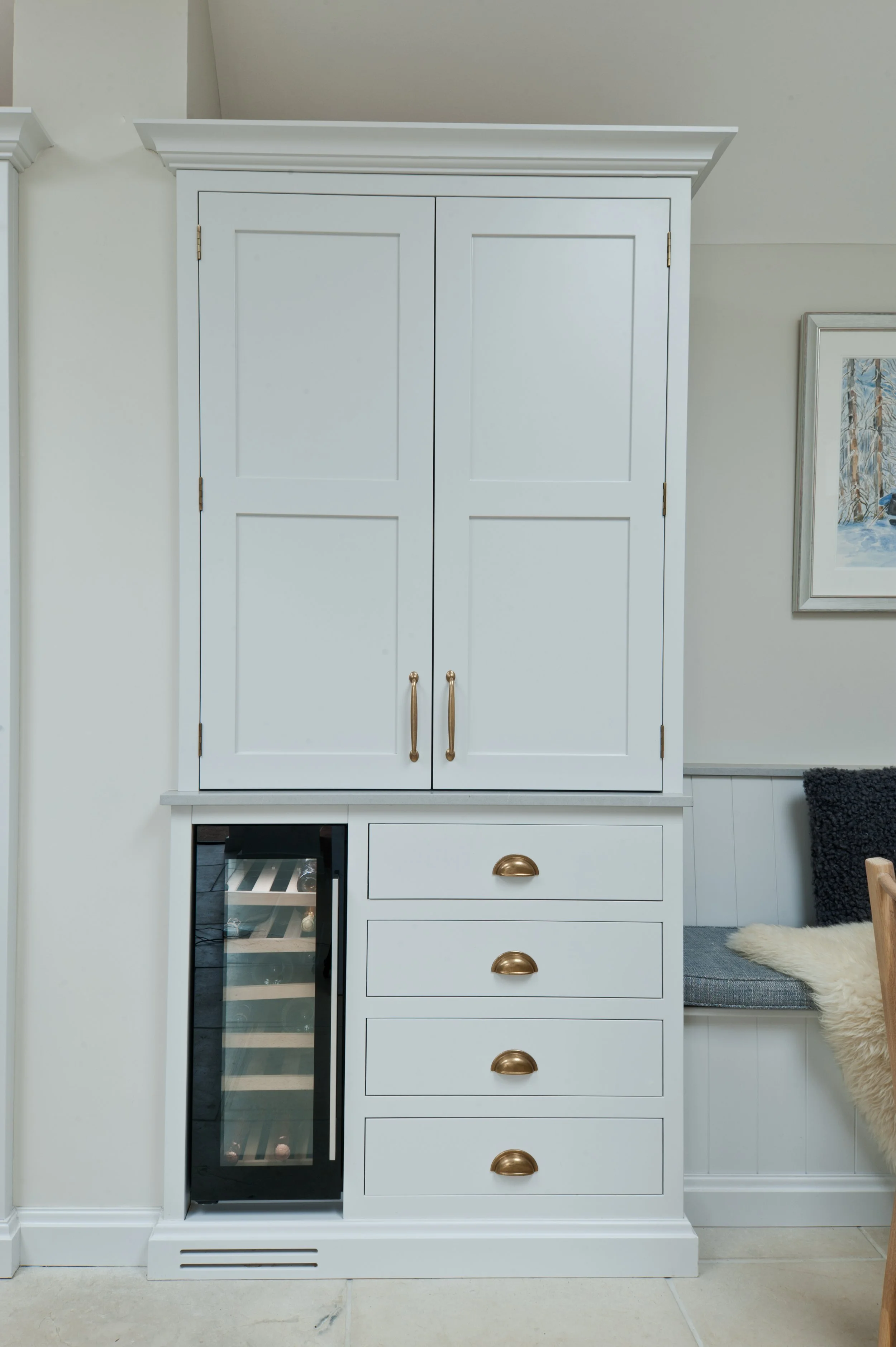 Floor-to-ceiling bespoke kitchen cabinetry with integrated wine cooler, drawers and brass handles.