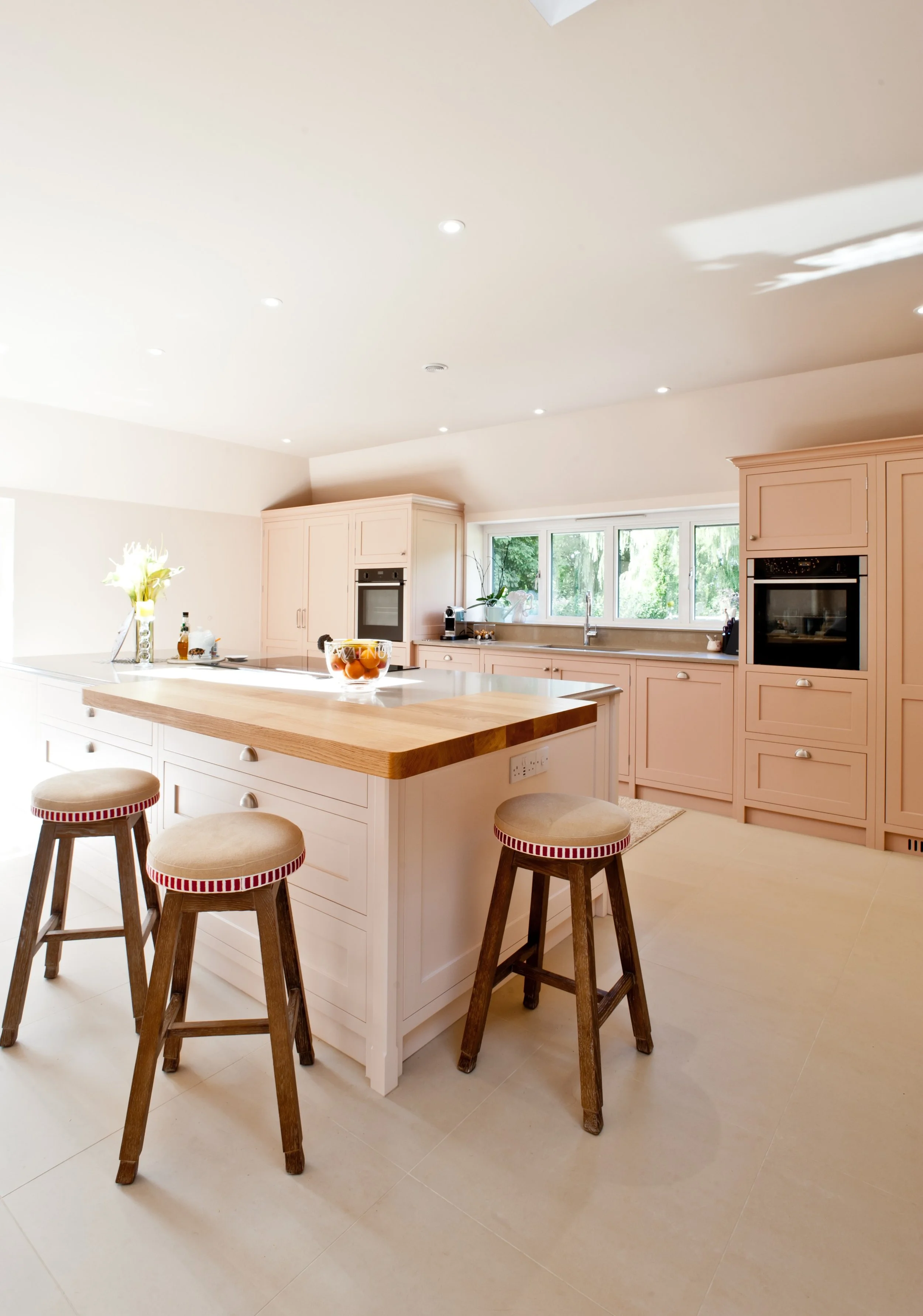 Bespoke kitchen island with painted cabinetry, timber worktop detail and upholstered bar stools.