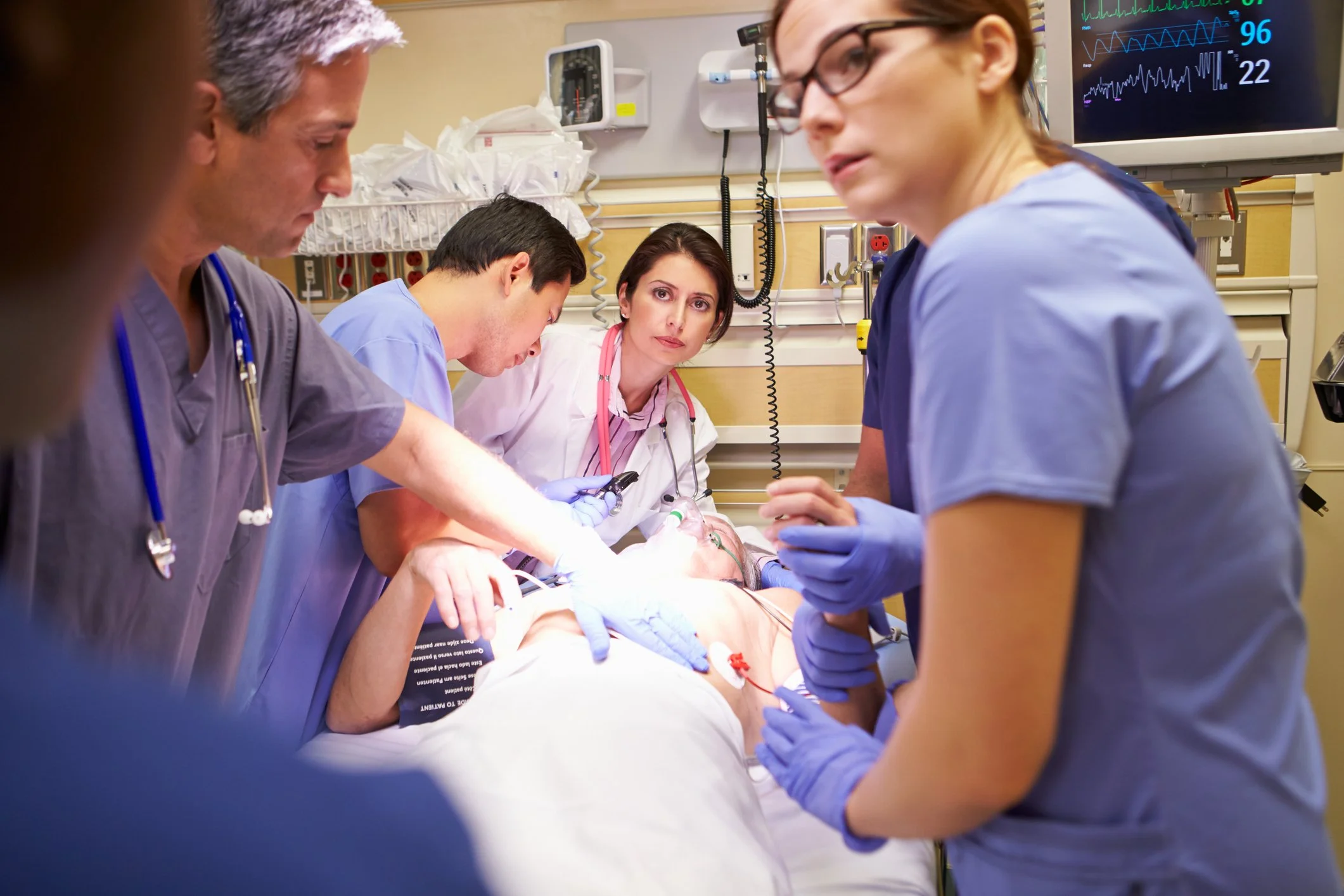 Medical team of doctors and nurses performing emergency procedures on a patient in a hospital setting.