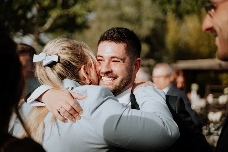 fotografía evento boda Hombre sonriendo mientras abraza a una mujer en una celebración al aire libre, Madrid, Raquel Botas.