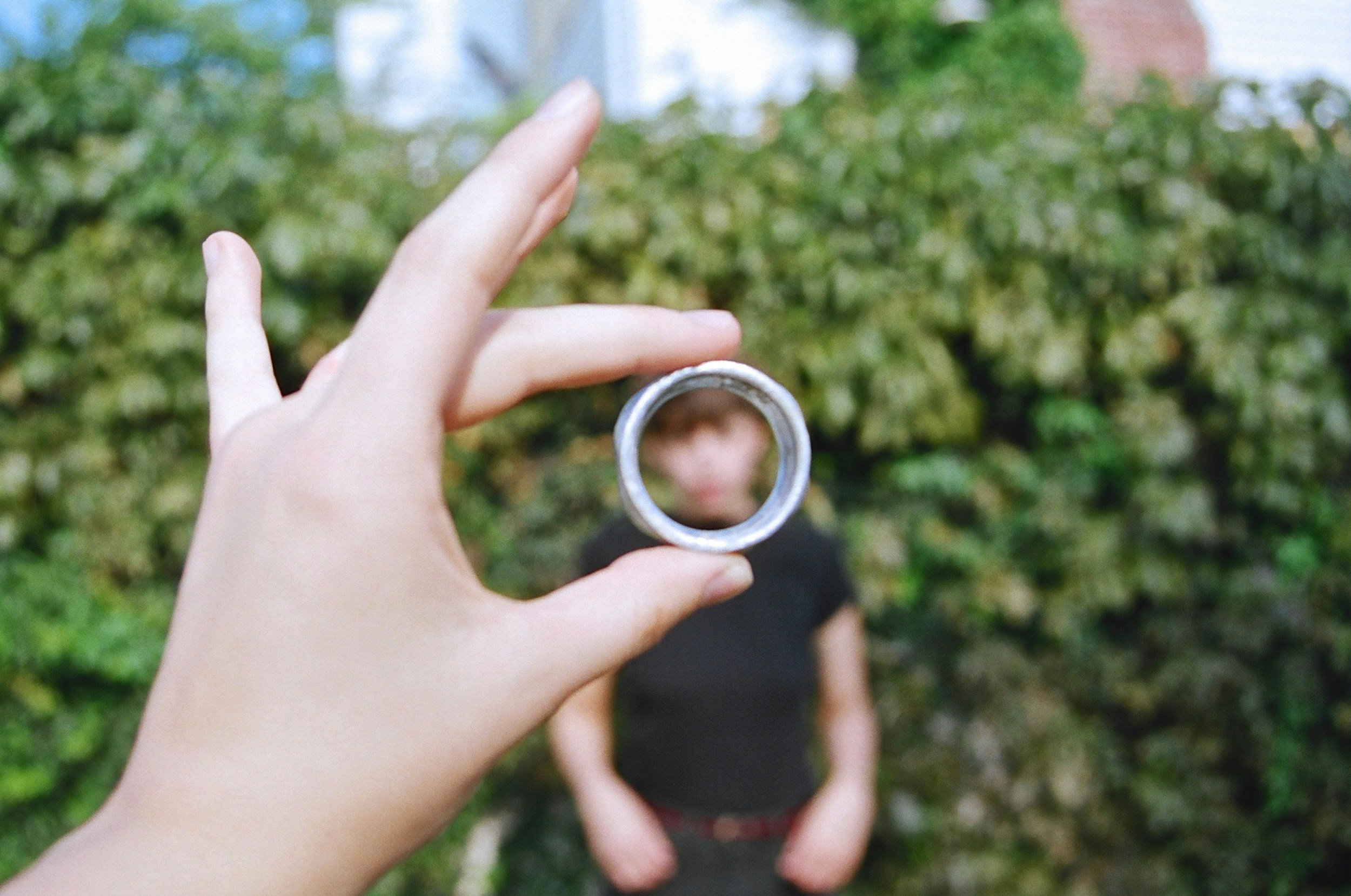 hand holding a magnifying glass with a person behind